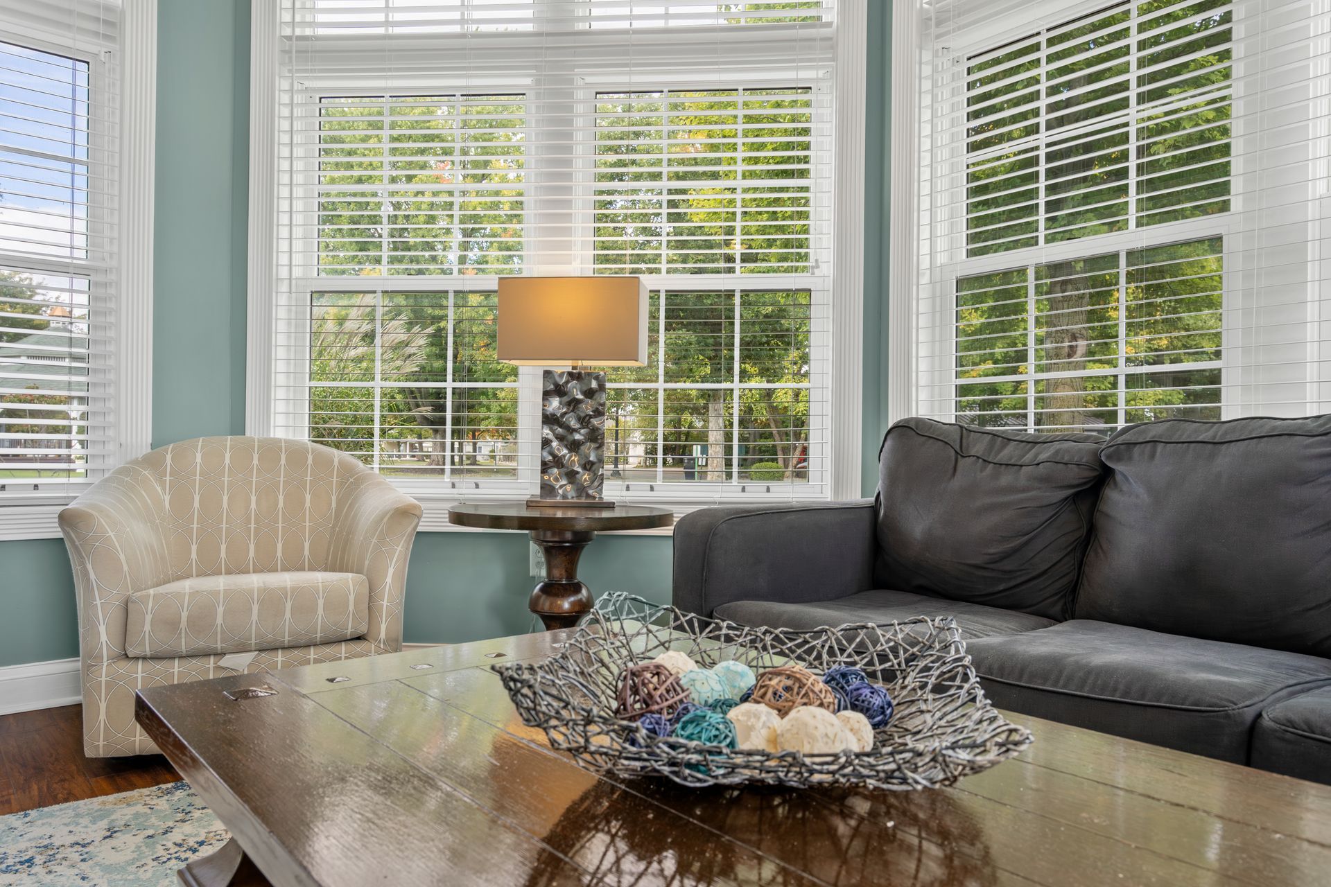 A living room with a couch , chair , table , lamp and bowl on the coffee table.