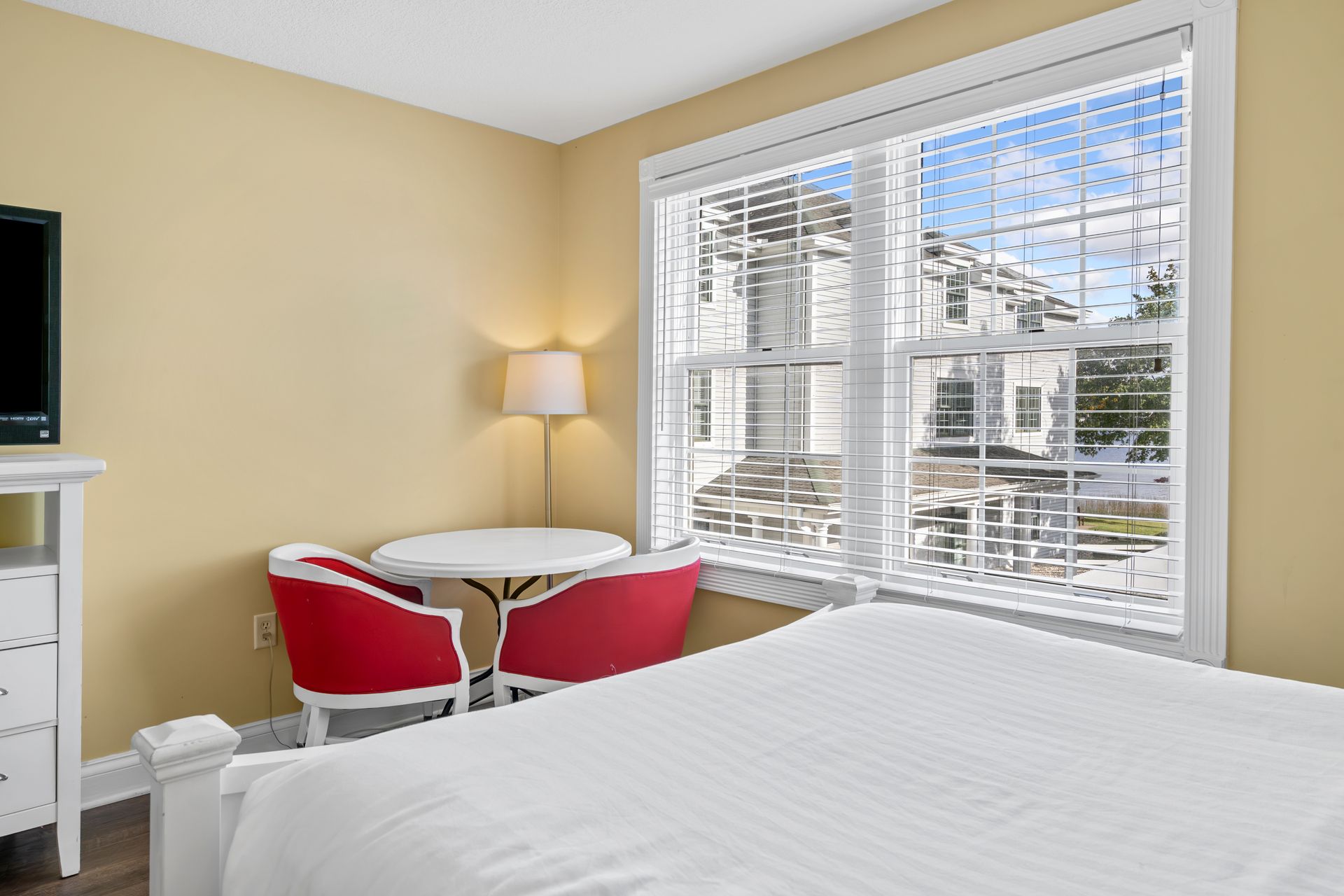 A hotel room with a bed , chairs , table and television.