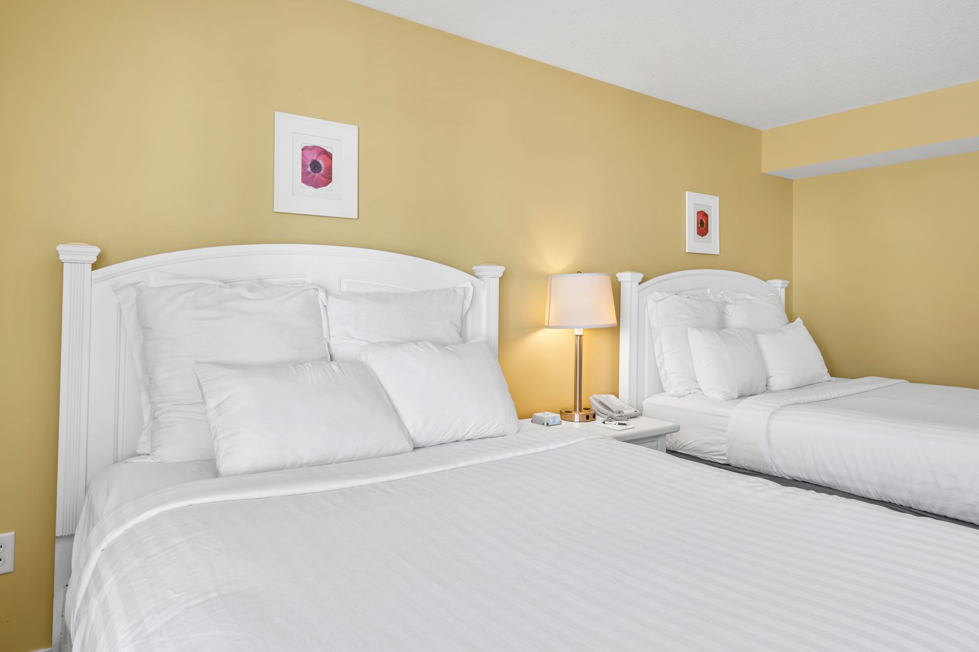 A hotel room with two beds and a lamp.