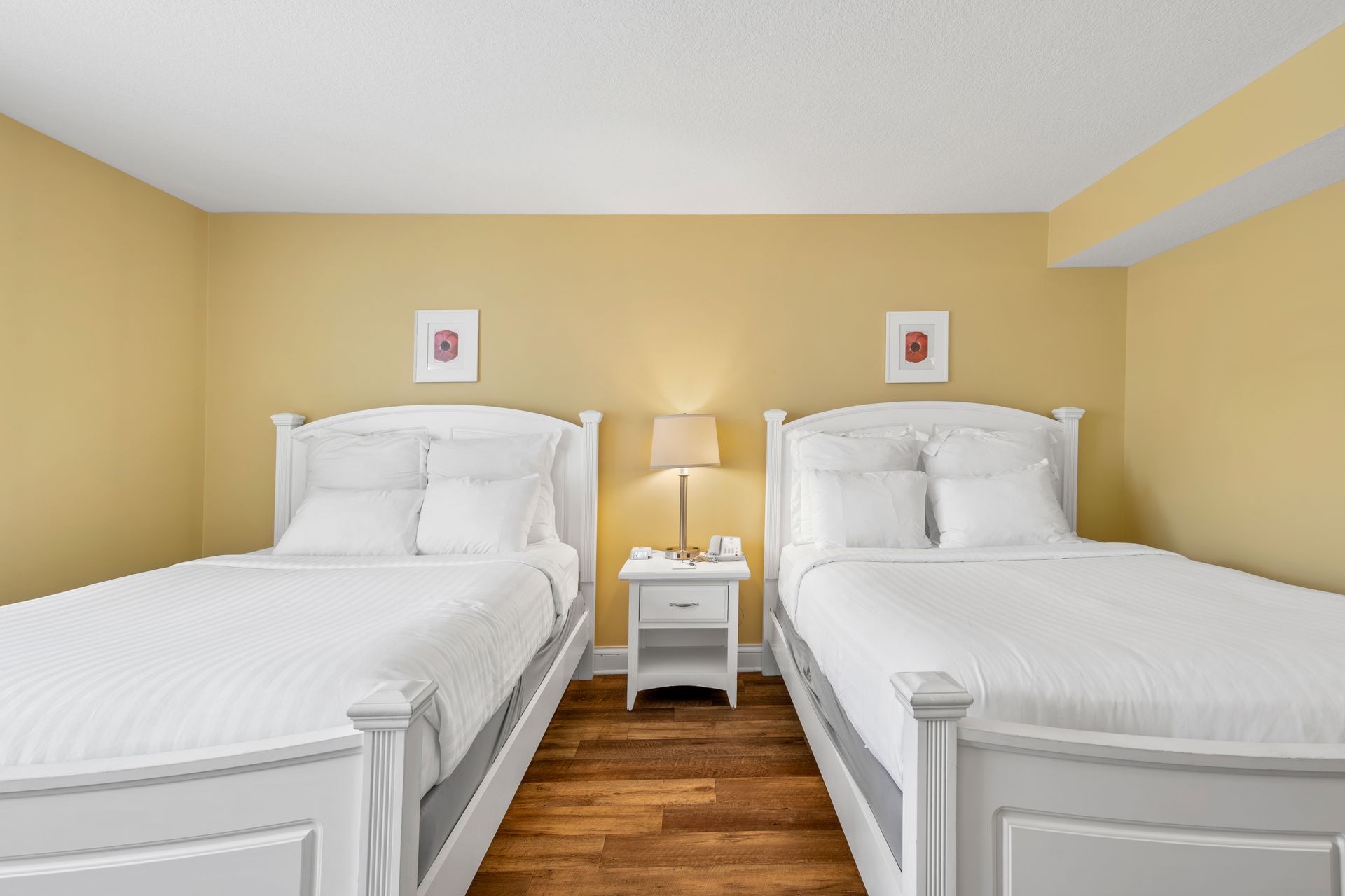 A bedroom with two beds , a nightstand and a lamp.
