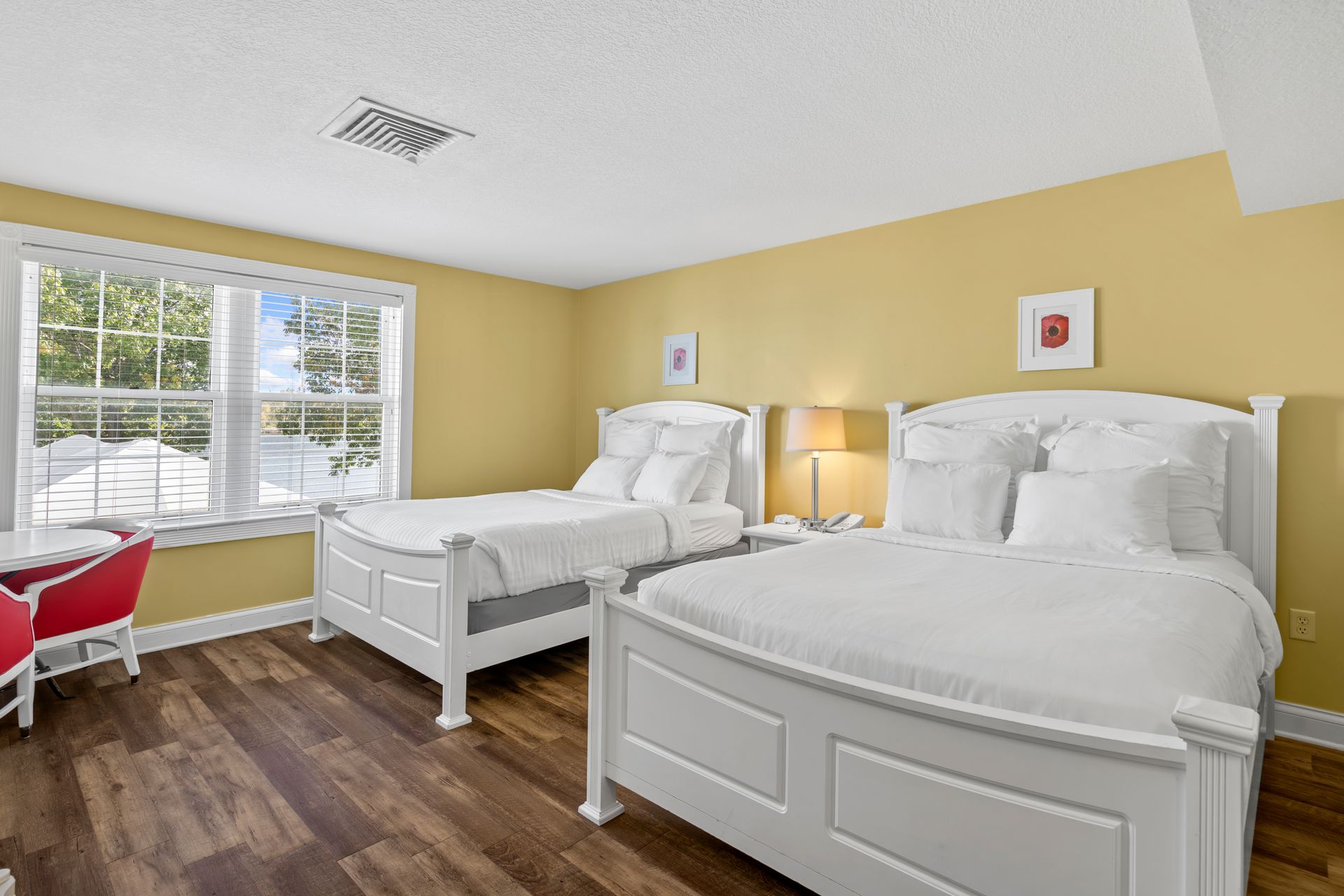 A bedroom with two beds , a table and a window.