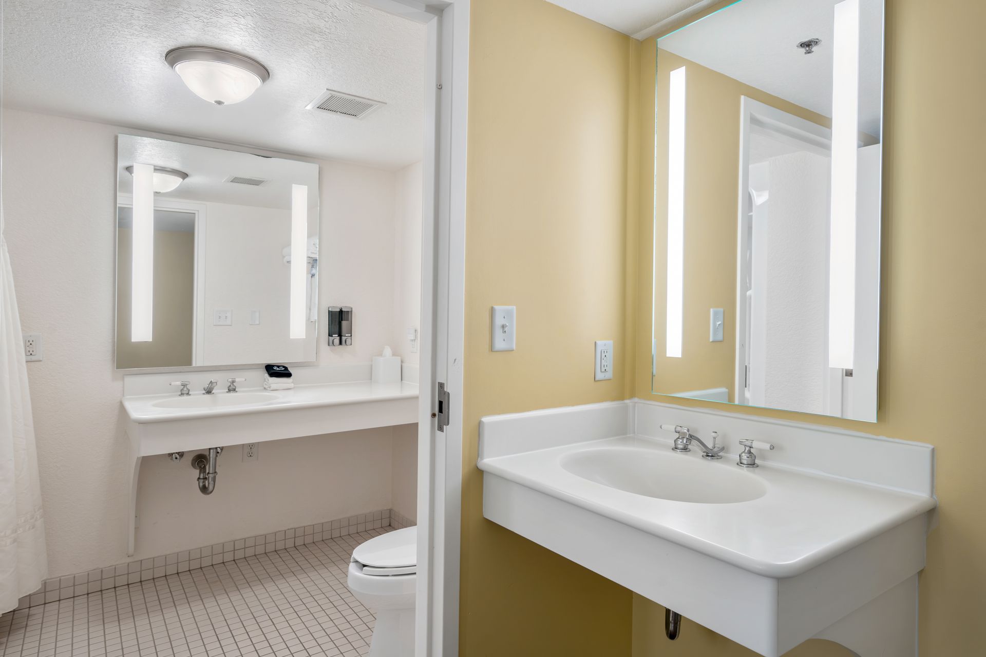 A bathroom in a hotel room with a sink , toilet and mirror.