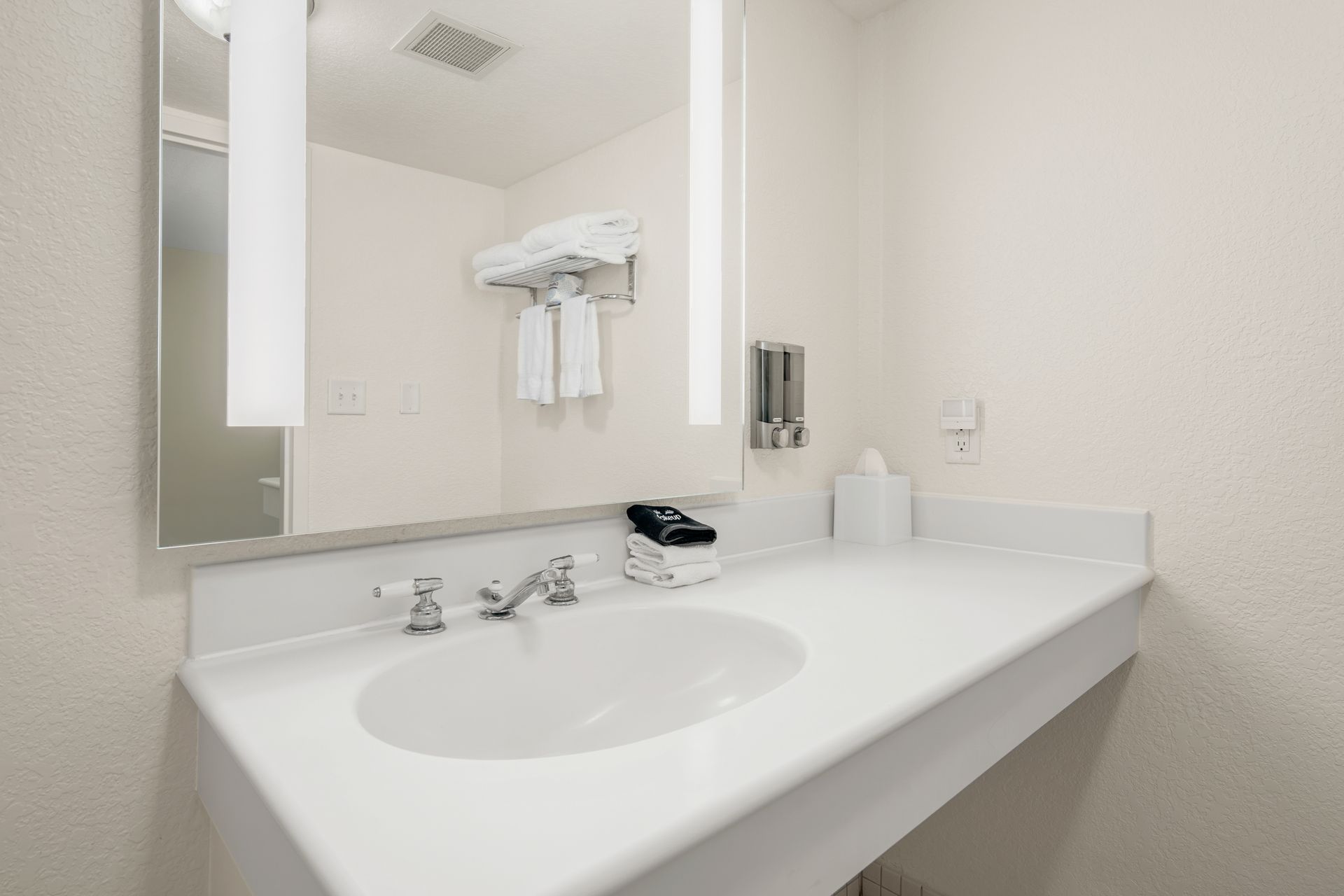 A bathroom with a sink , mirror and towel rack.