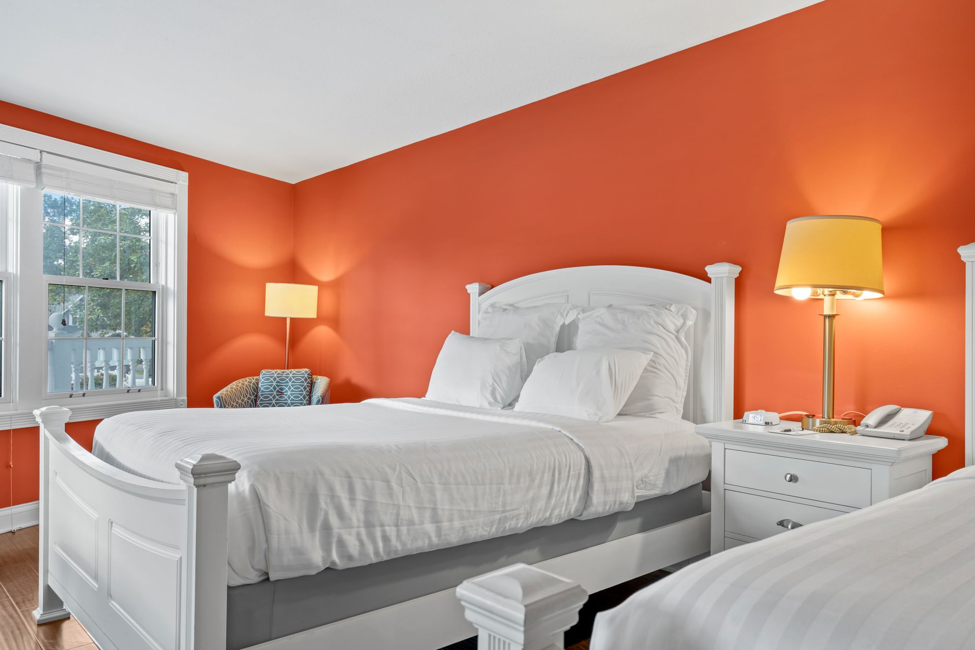 A bedroom with two beds and orange walls.