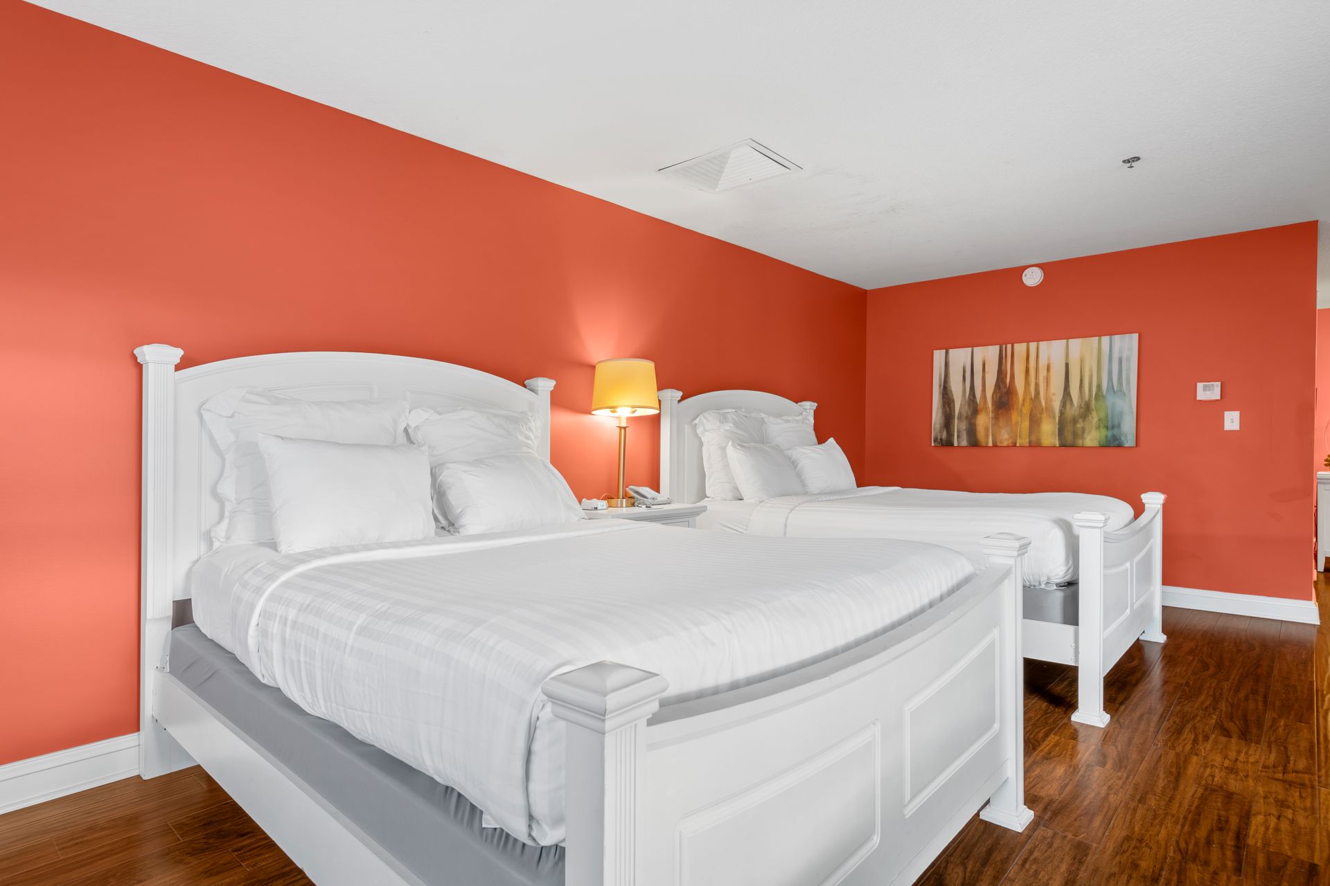 There are two beds in a hotel room with red walls.