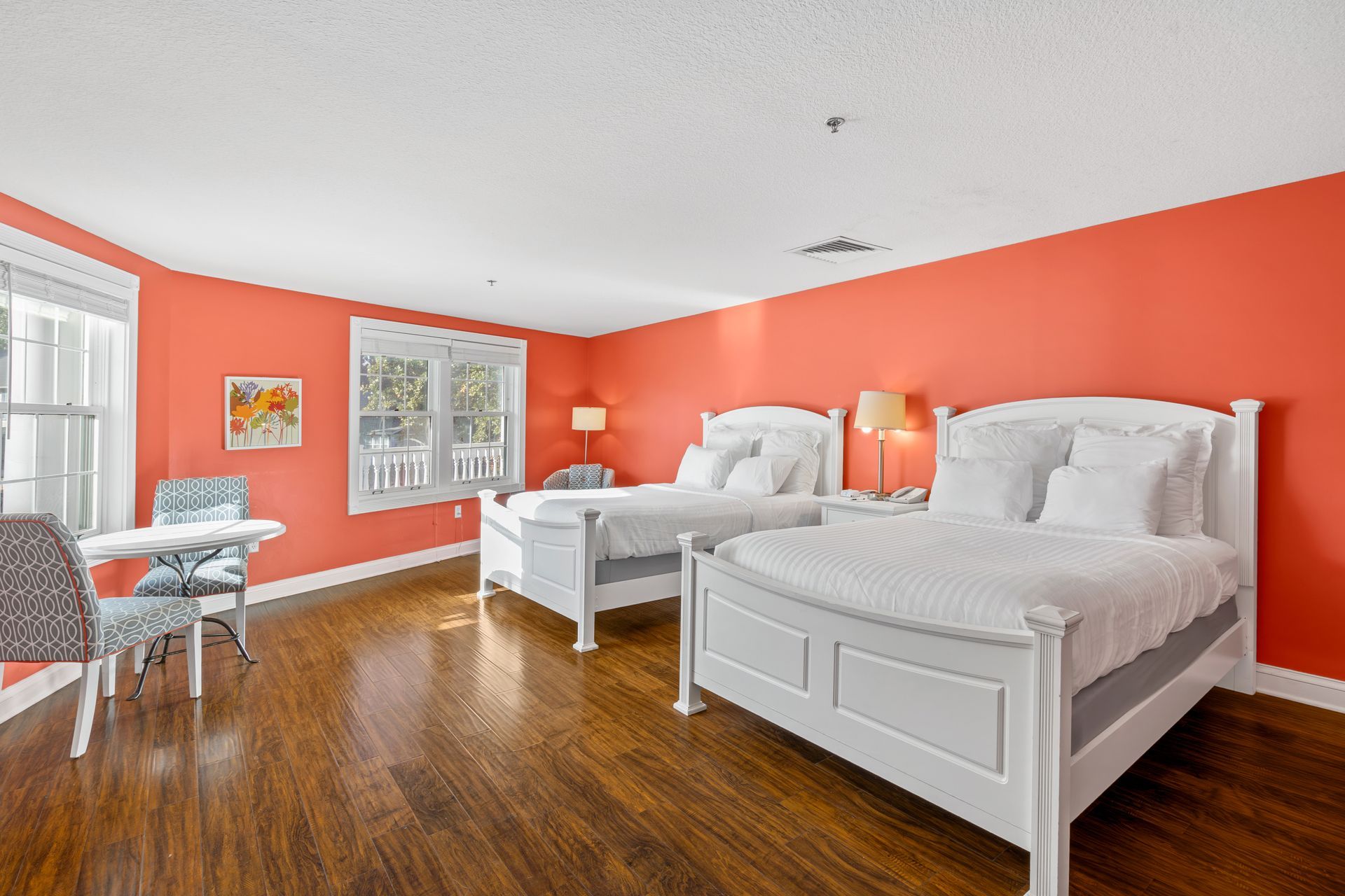 There are two beds in the room with red walls.