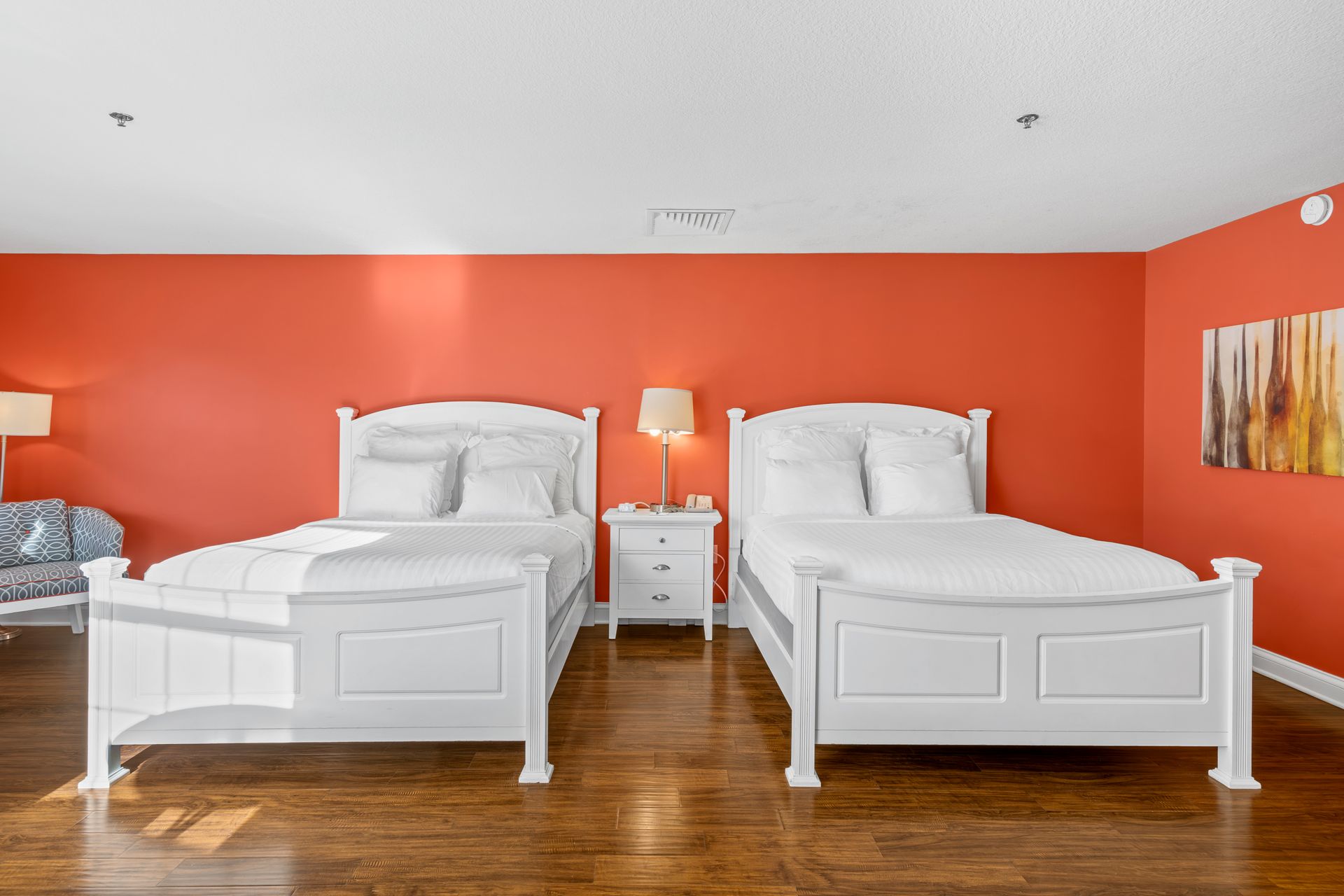 There are two beds in the room with red walls.