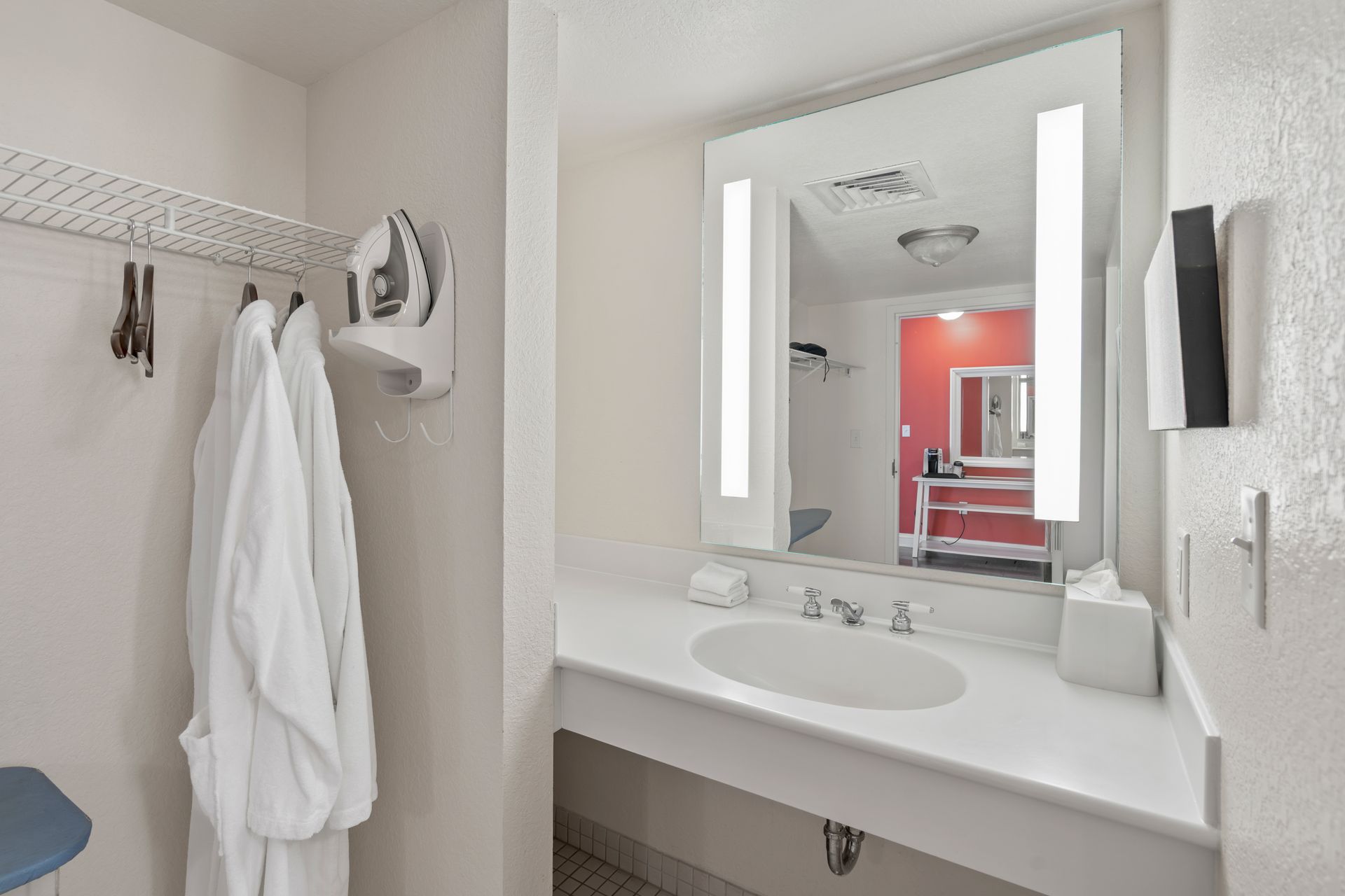 A bathroom in a hotel room with a sink and a mirror.