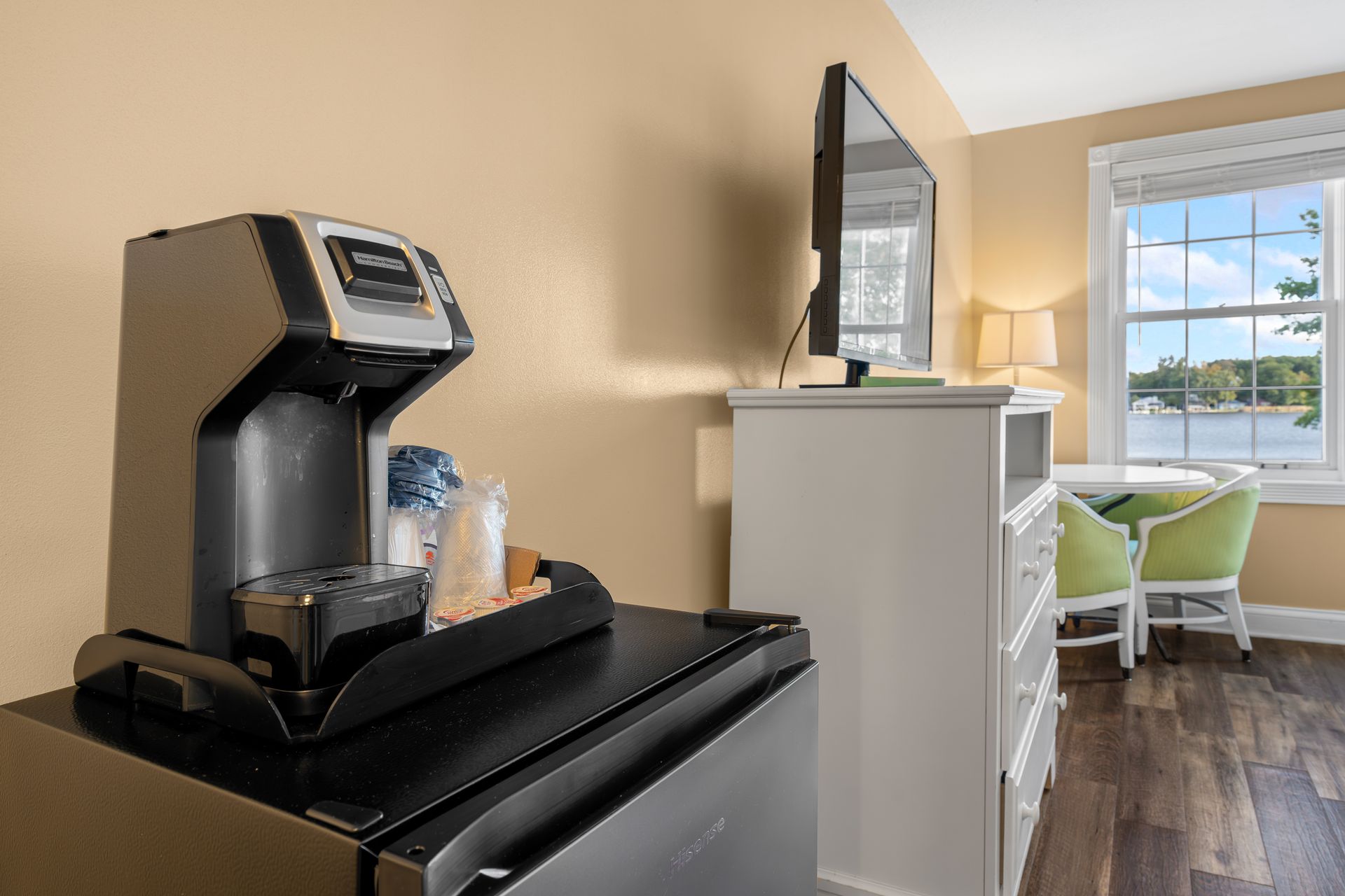 A hotel room with a coffee maker and a refrigerator.