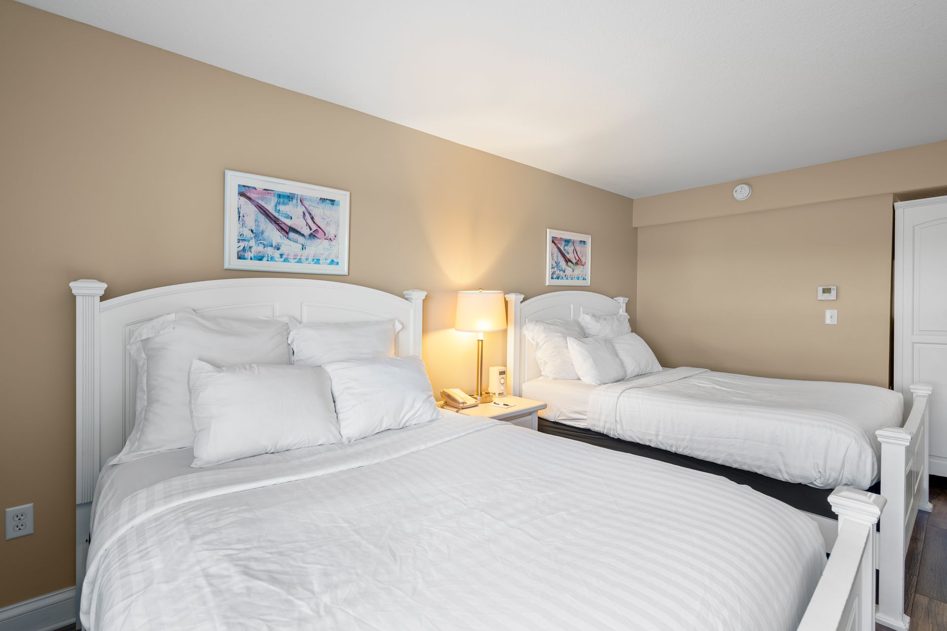 A hotel room with two beds and two lamps.