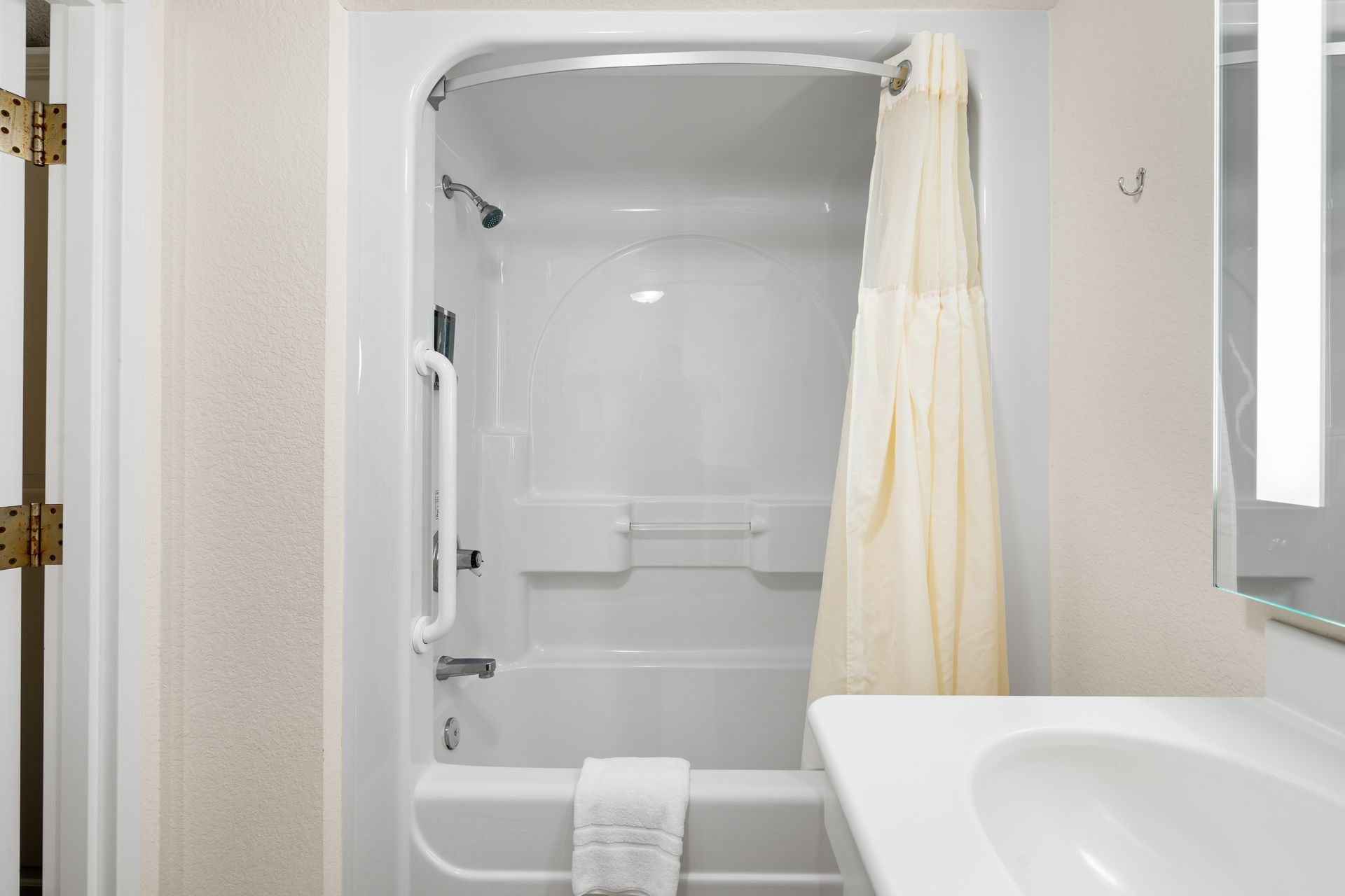 A bathroom with a tub , sink , mirror and shower curtain.