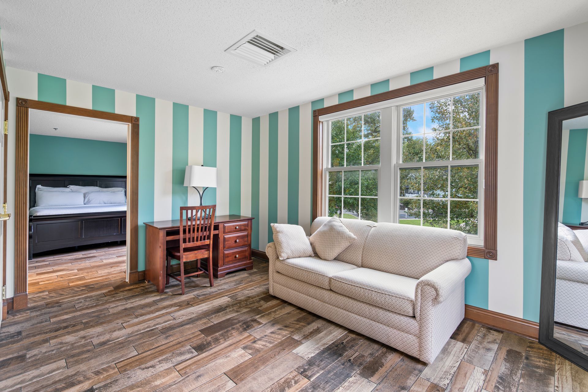 A living room with a couch , desk , chair and striped walls.