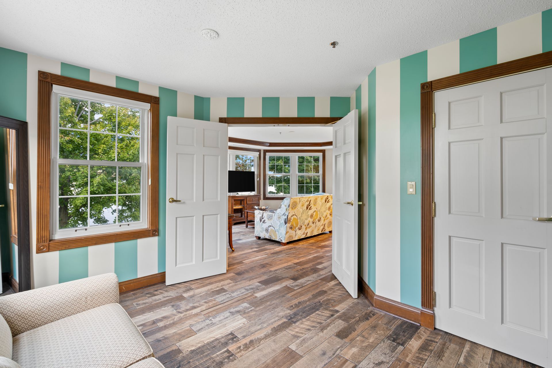A living room with striped walls and wooden floors