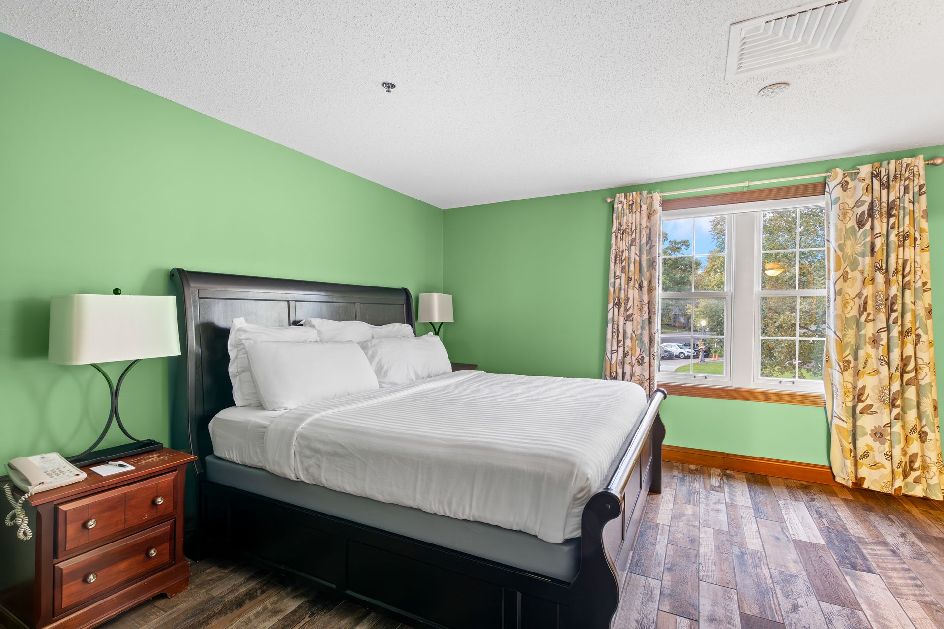 A hotel room with green walls and a king size bed.