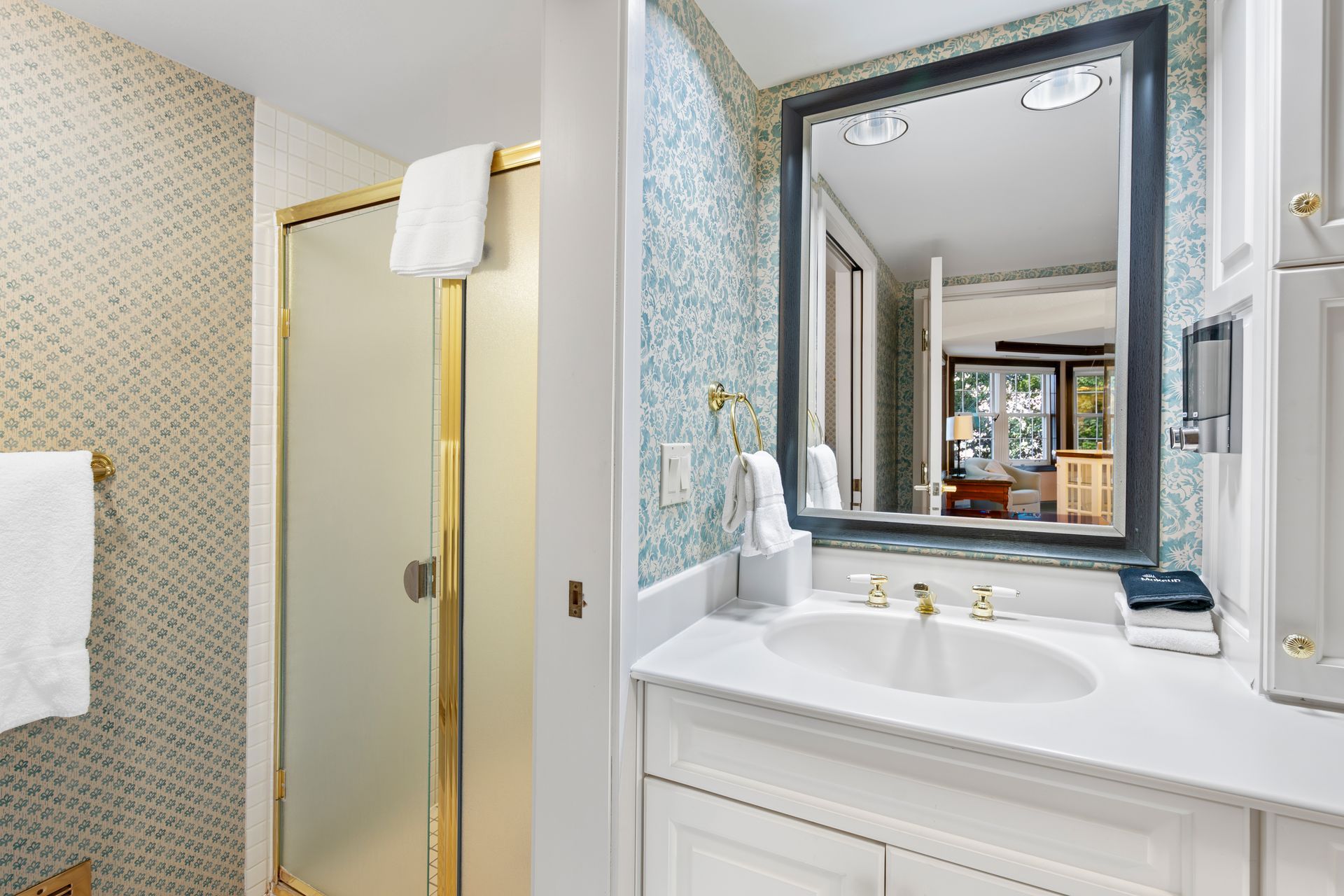 A bathroom with a sink , mirror and shower.