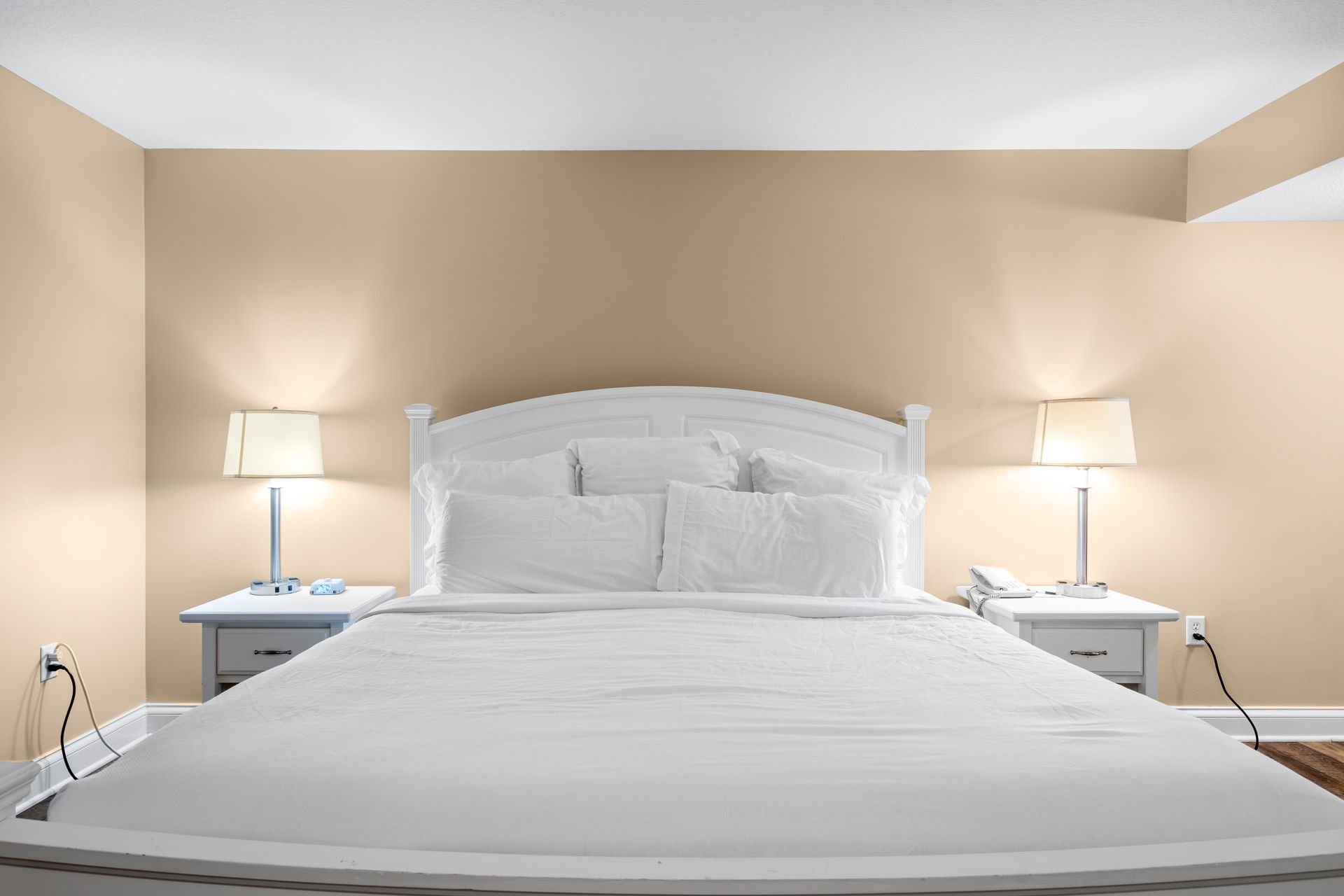 A bedroom with a king size bed , two nightstands , and two lamps.
