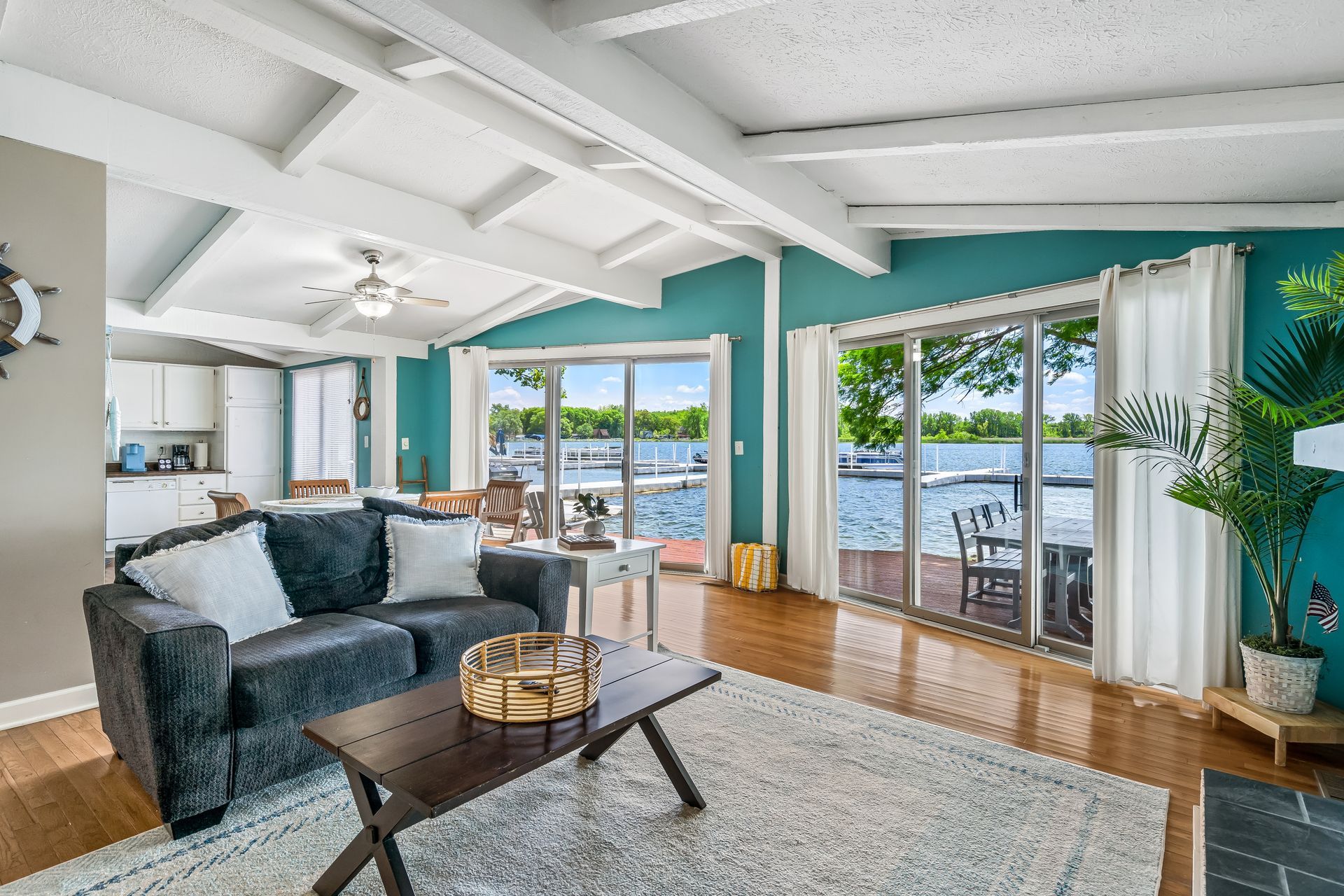 A living room with a couch , coffee table , and sliding glass doors overlooking a lake.