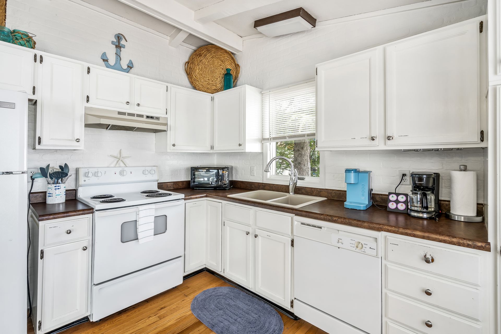 A kitchen with white cabinets , a stove , a refrigerator , and a sink.