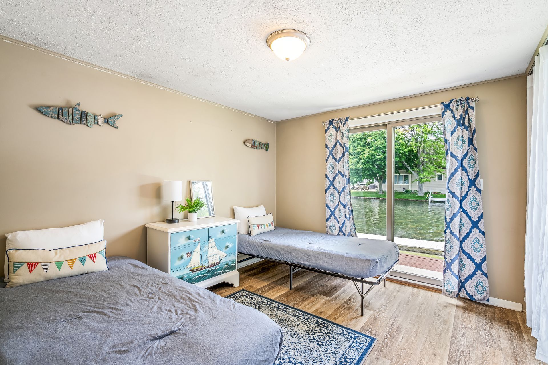 A bedroom with two beds , a dresser , and a sliding glass door.