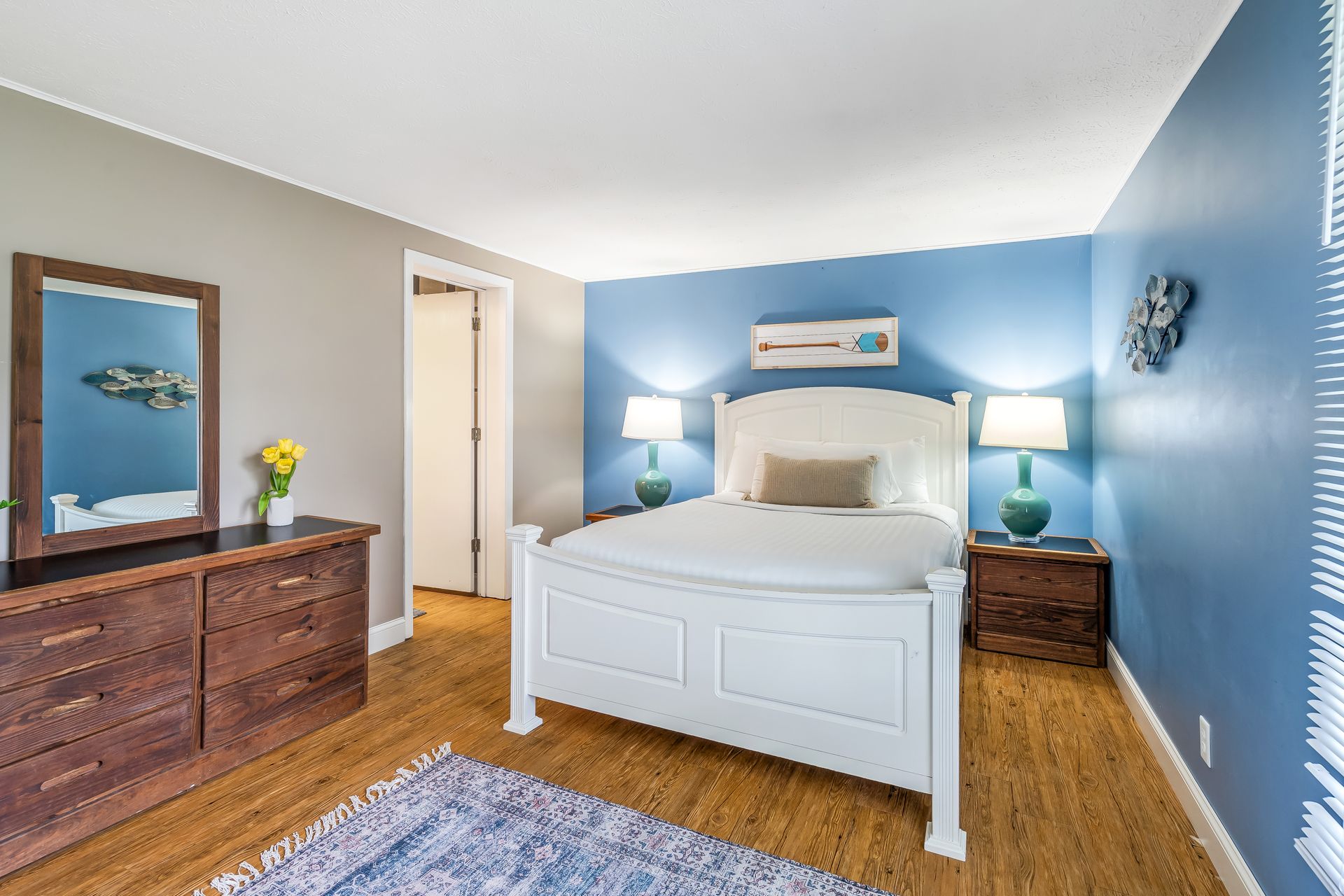 A bedroom with a bed , dresser , mirror and nightstand.