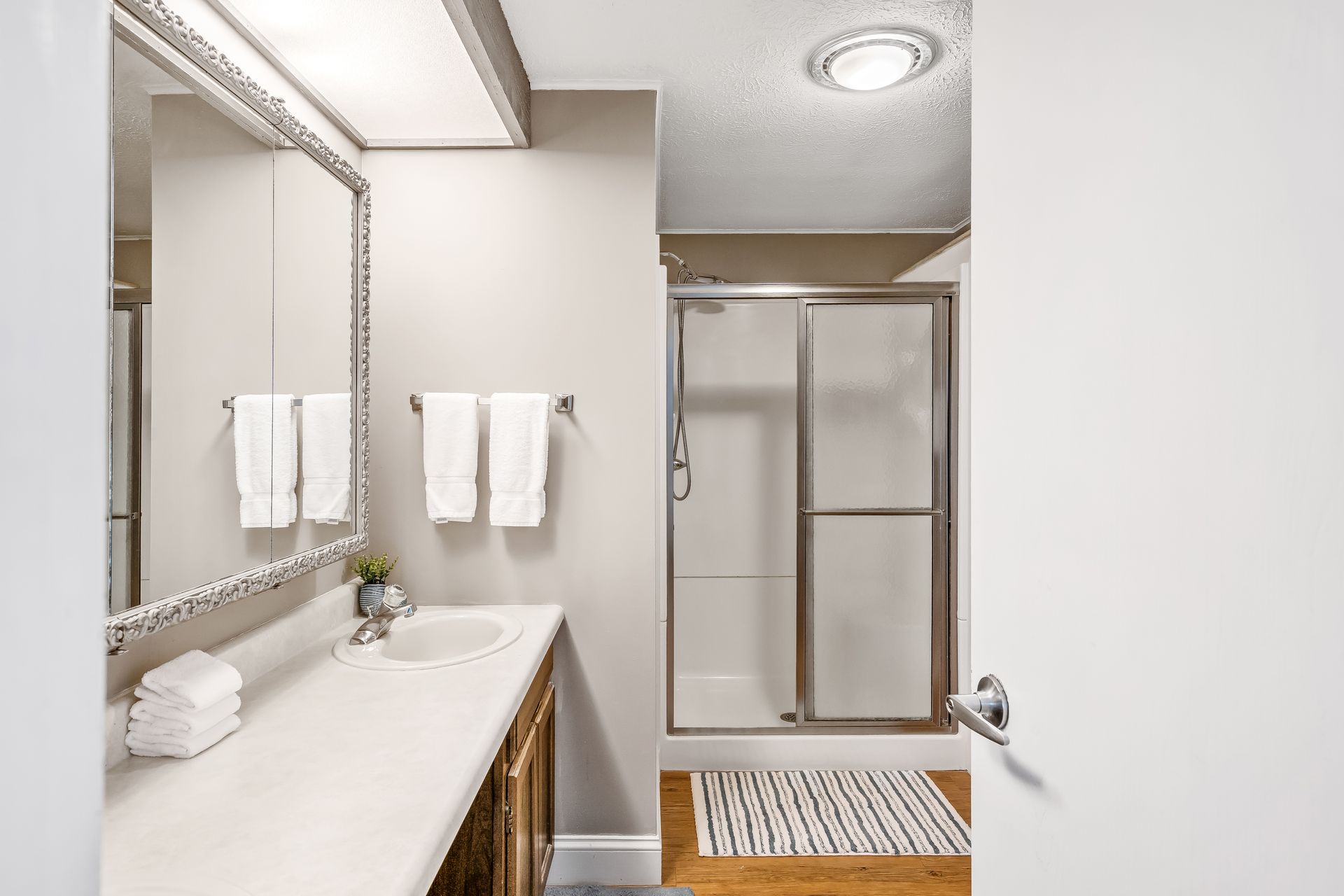 A bathroom with a sink , mirror , and shower.