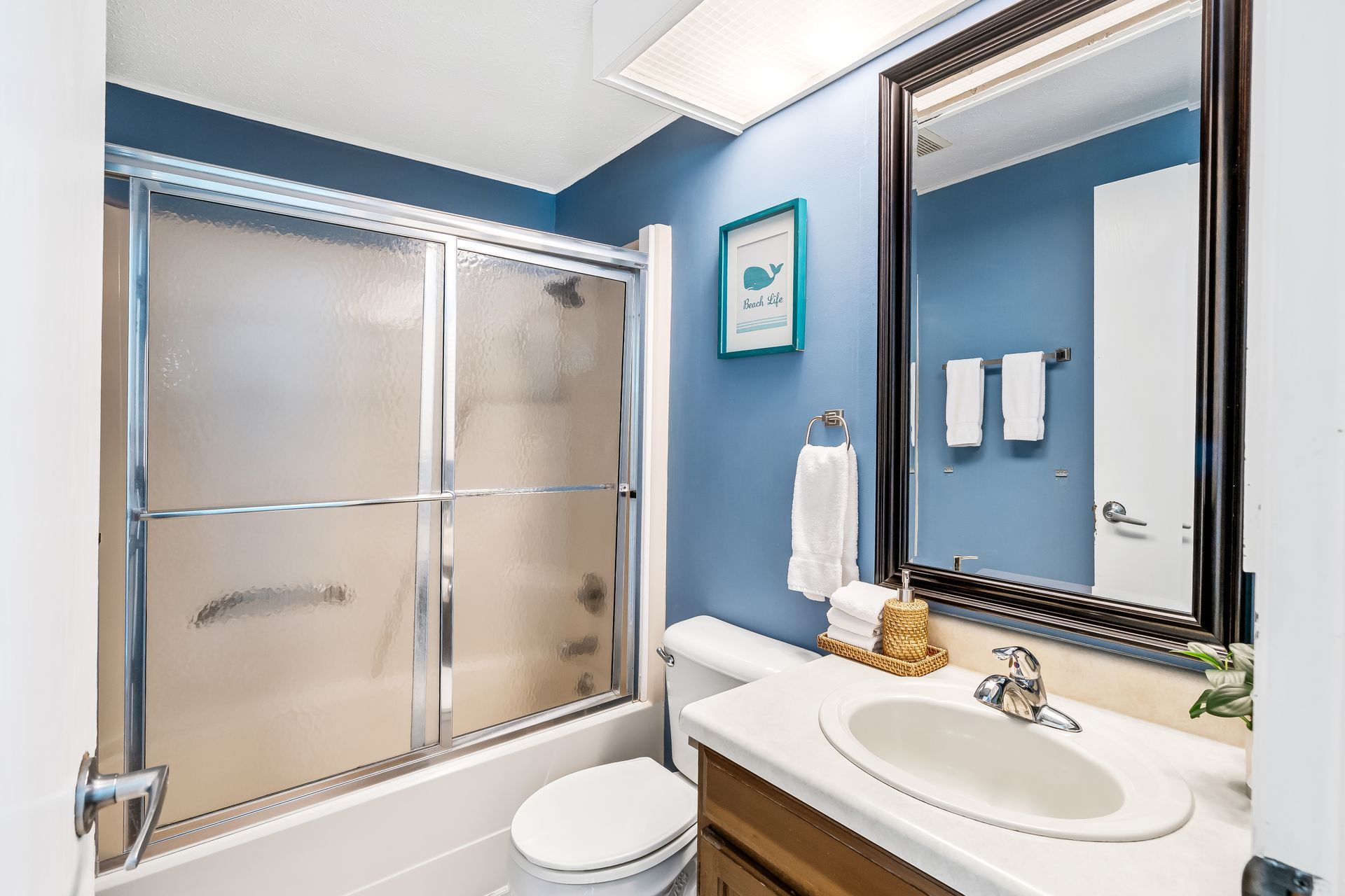 A bathroom with a toilet , sink , shower and mirror.