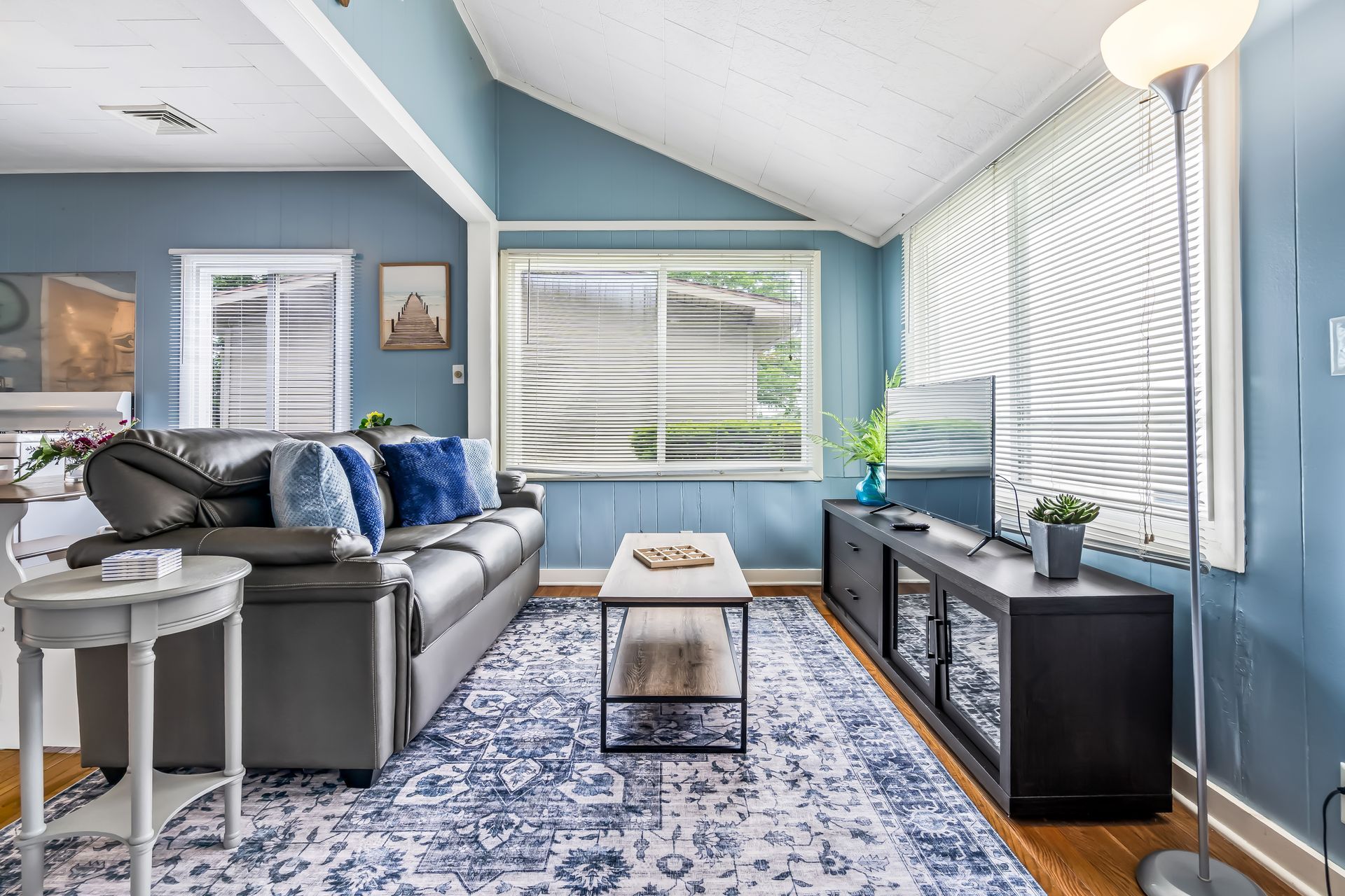 A living room with blue walls , a couch , a coffee table , and a rug.