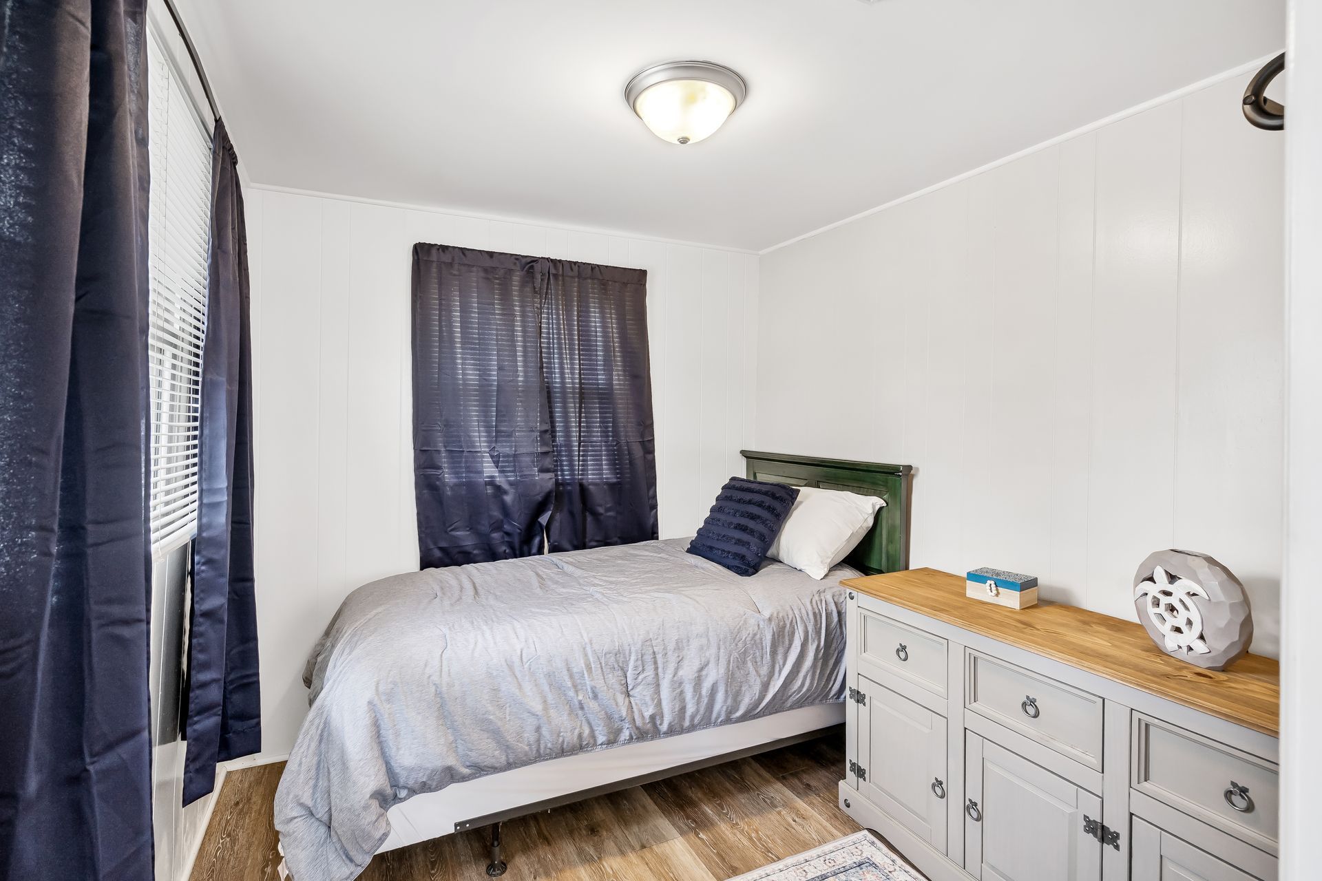 A bedroom with a bed , dresser , and window.