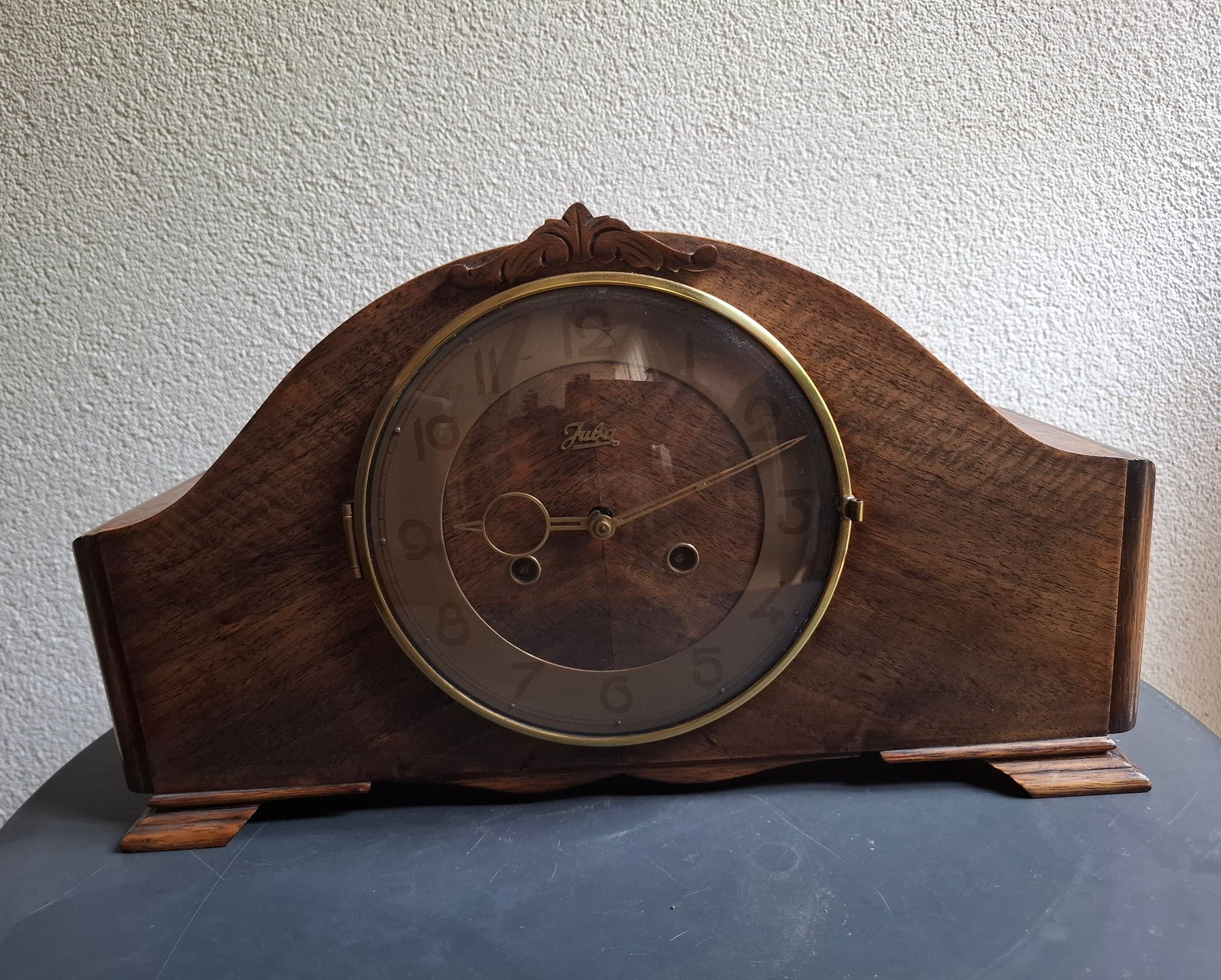 Antieke houten klok met ronde wijzerplaat en gouden afwerking.