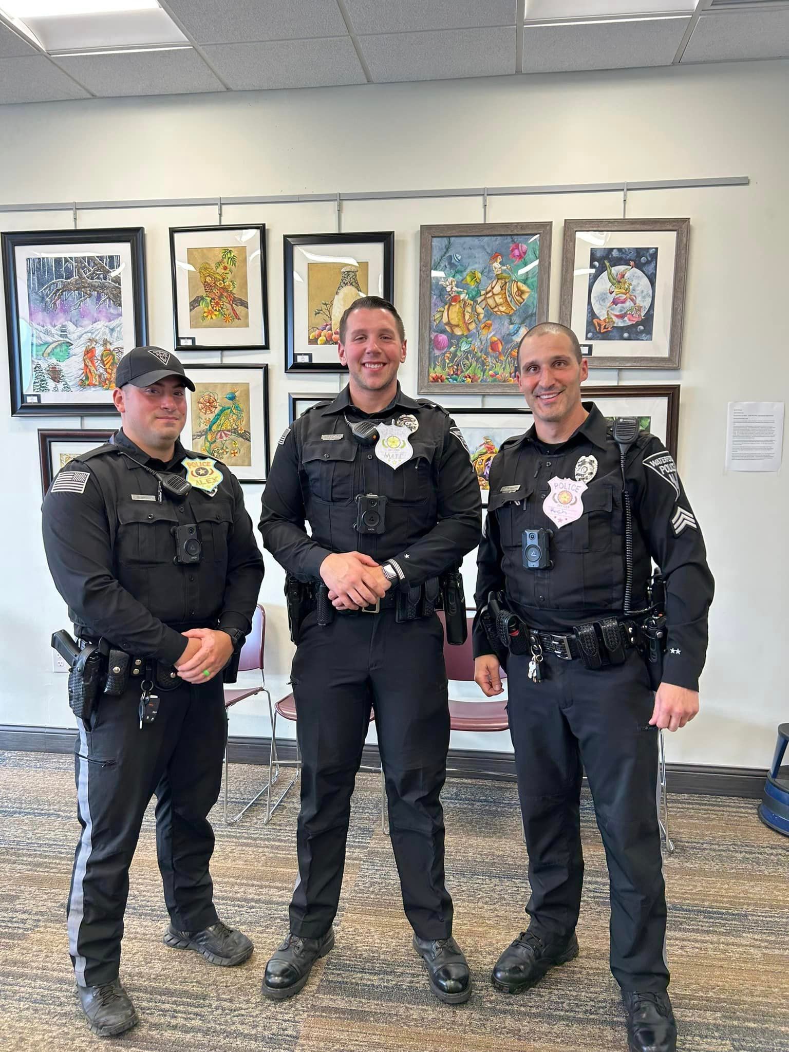 three police officers are posing for a picture in front of paintings