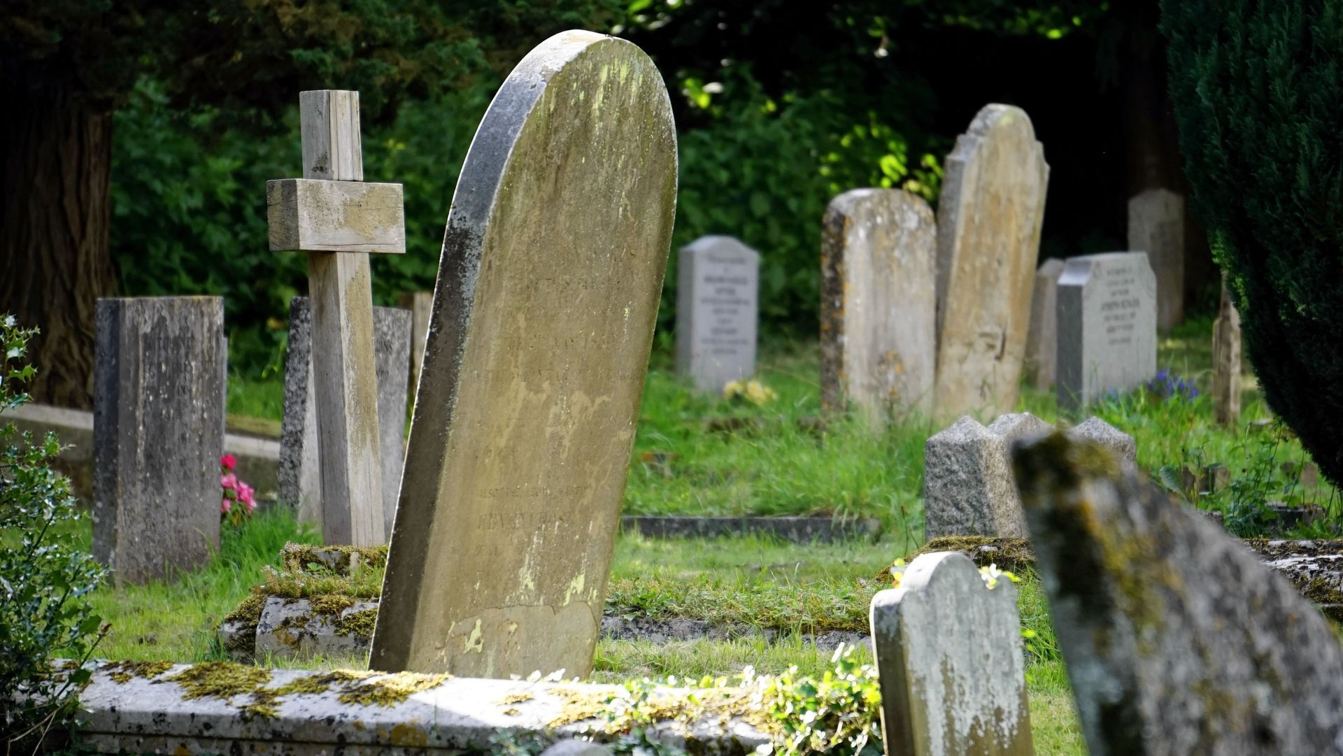 Gravestones in a grassy cemetery, including a large tilted stone in the foreground.