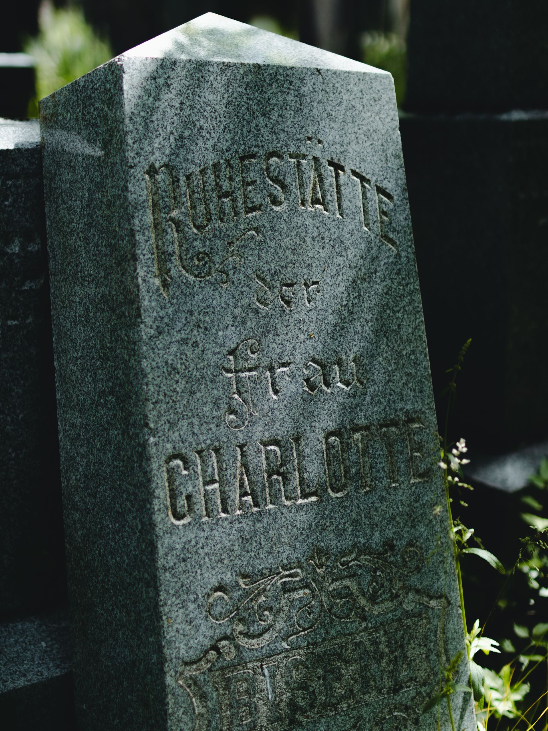 Weathered gray gravestone with engraved text in a cemetery