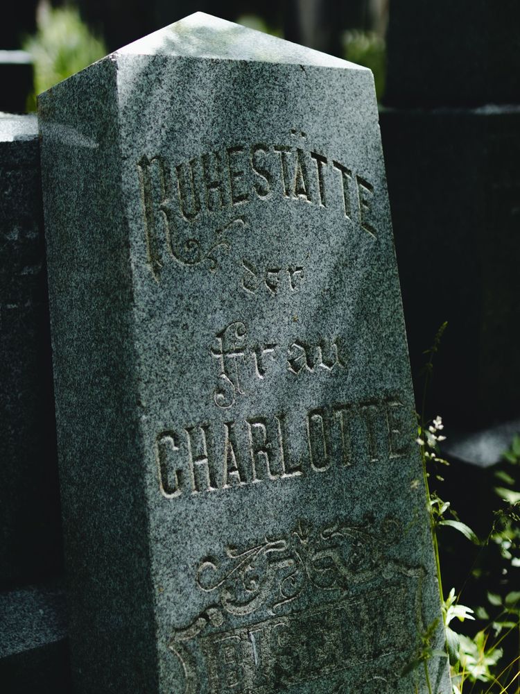 Weathered stone gravestone with carved text in a dark outdoor setting