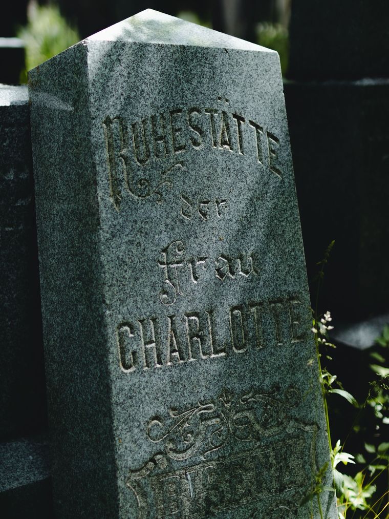 Weathered gravestone with the engraved name “CHARLOTTE” in a cemetery setting