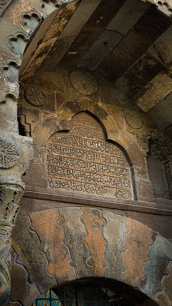 Ancient carved stone arch with an Arabic inscription in a historic interior doorway