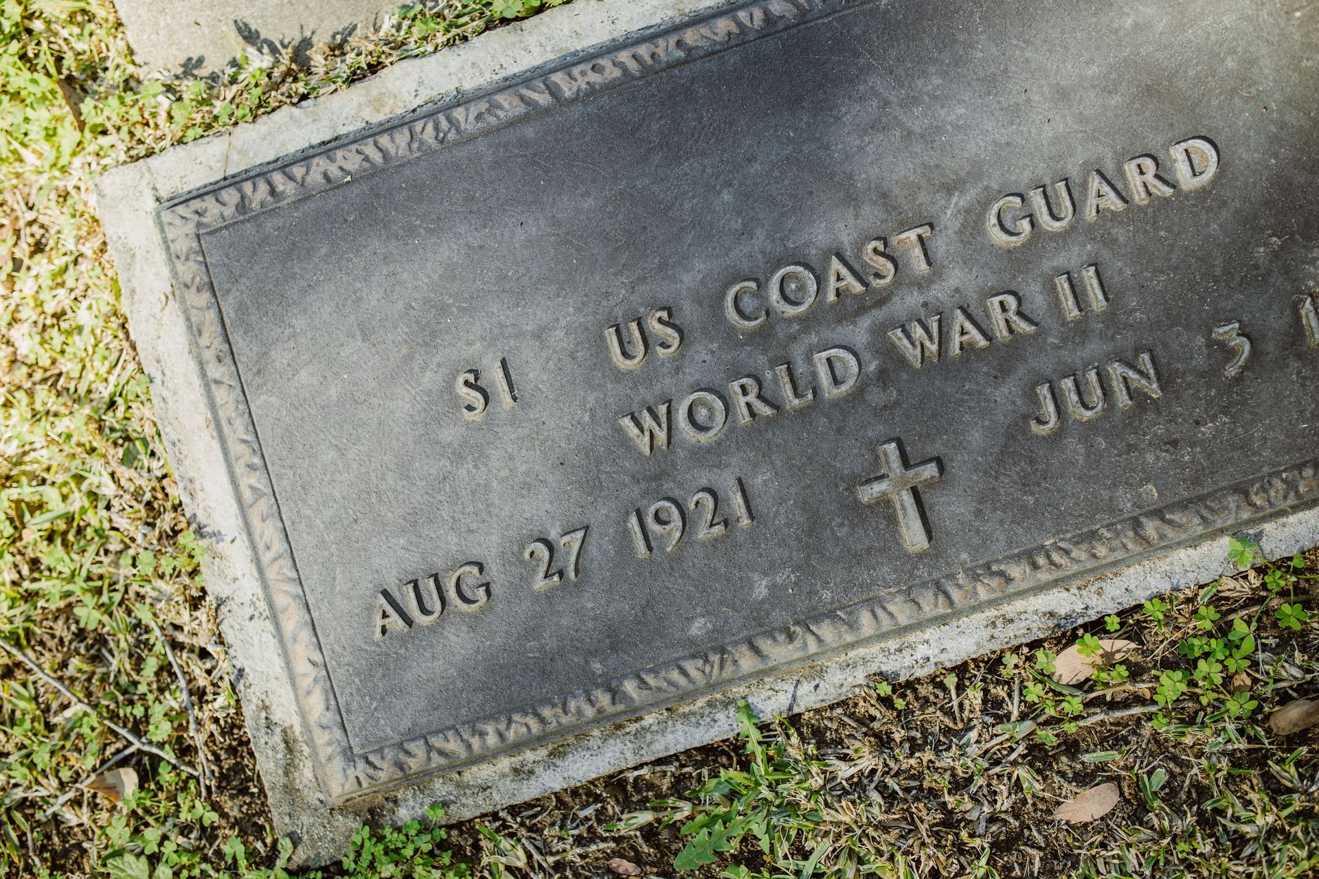 Weathered granite U.S. Coast Guard World War II grave marker in a grassy cemetery
