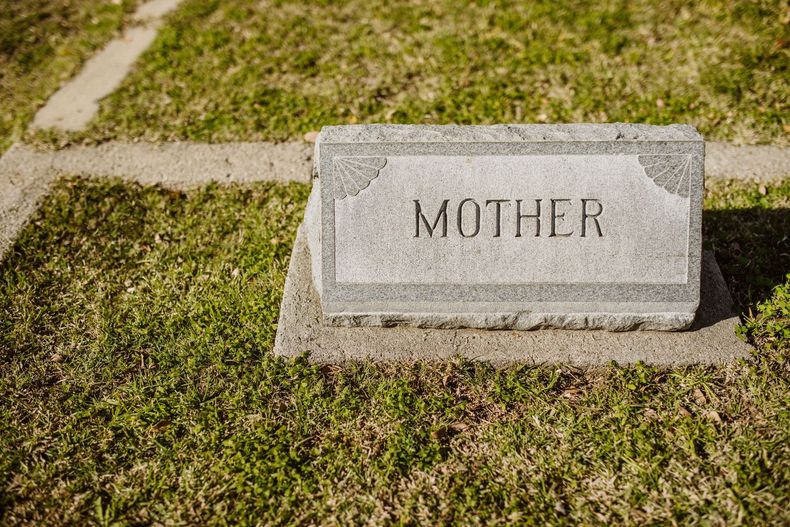 Gravestone marker engraved “MOTHER” in a grassy cemetery.