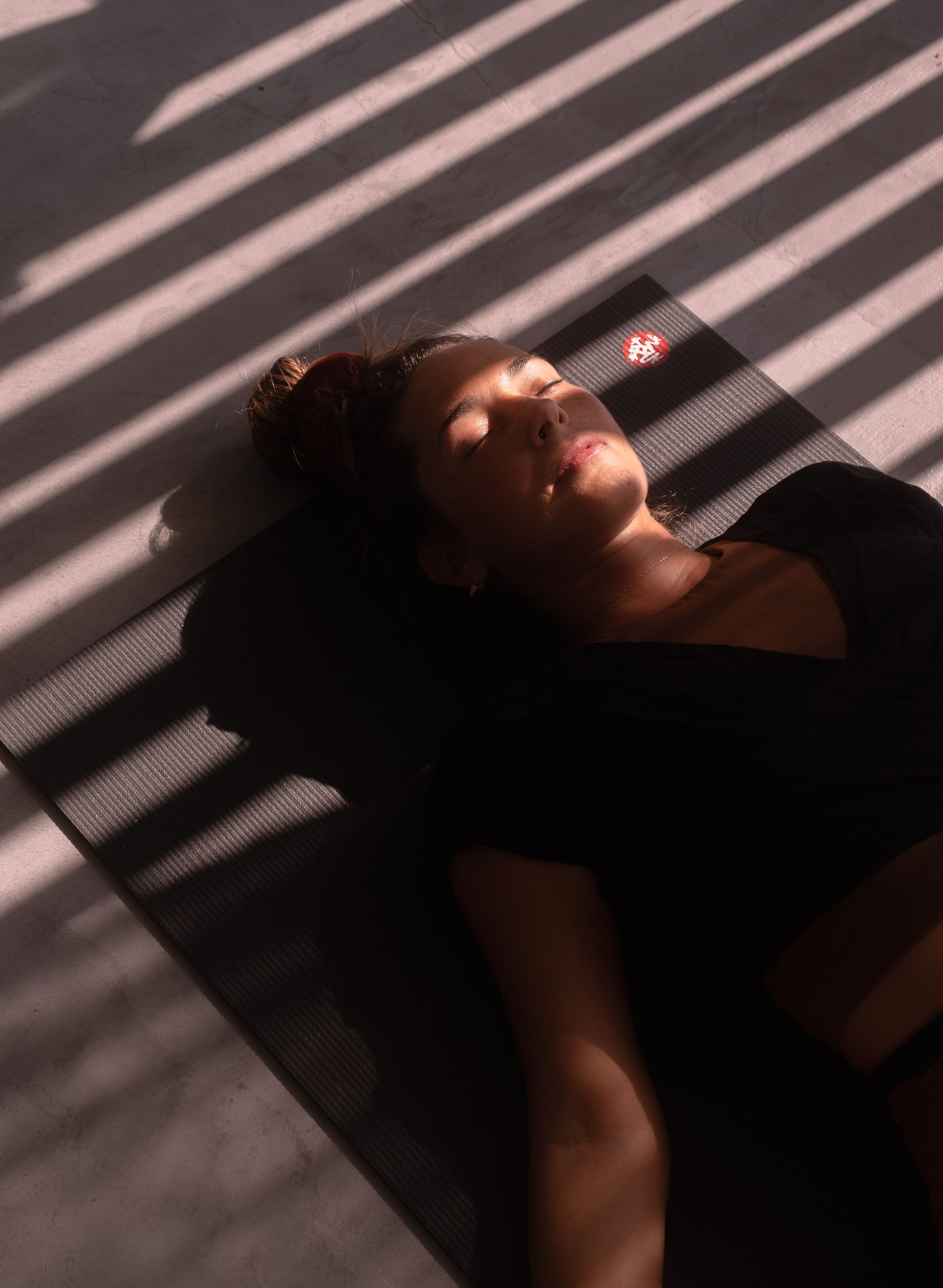 Woman resting peacefully in patterned sunlight during a yoga retreat