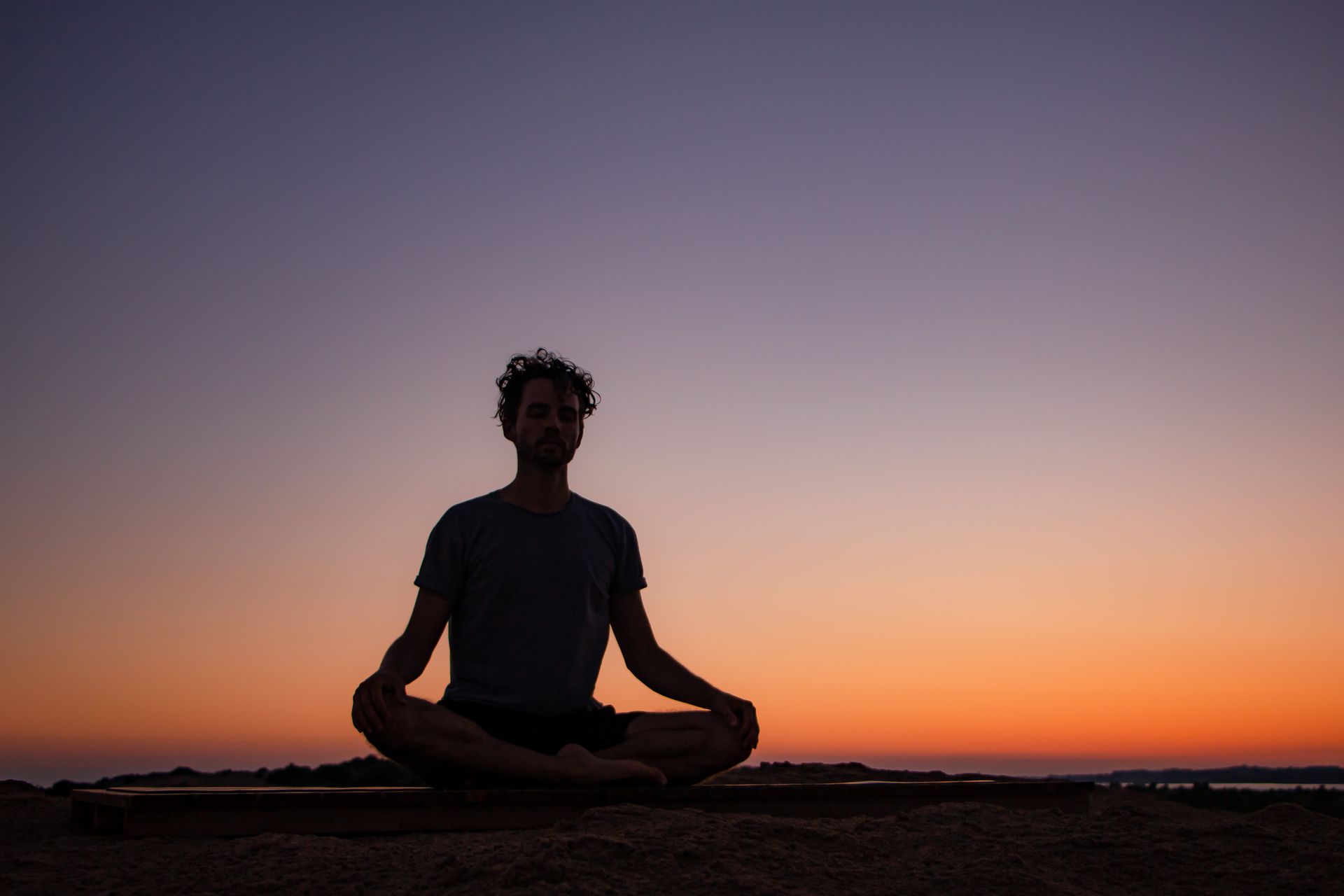 Man meditating at sunset on Issos Beach during a yoga retreat in Corfu