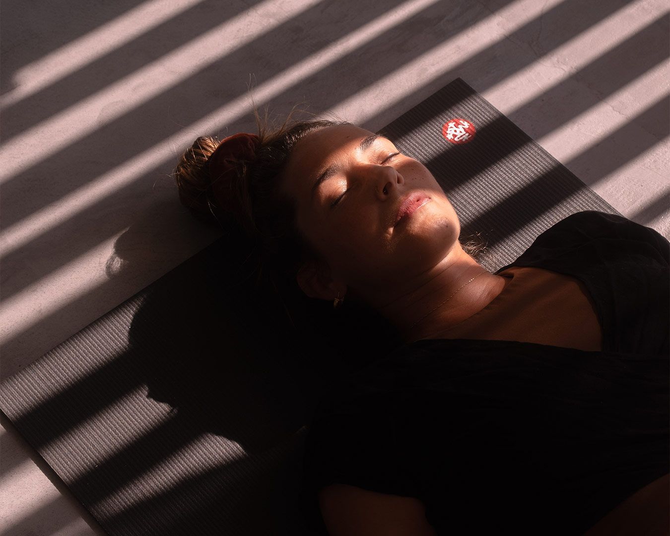 Woman resting peacefully in patterned sunlight during a yoga retreat