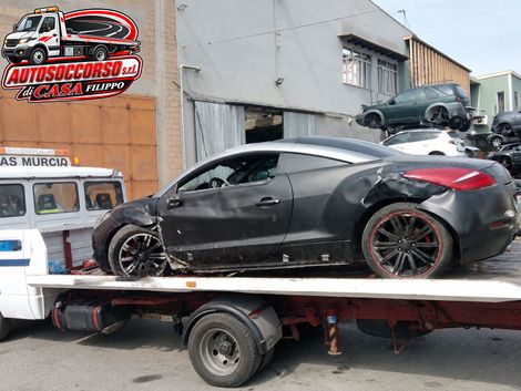 Automobilista accanto a un'auto ferma con carroattrezzi sullo sfondo
