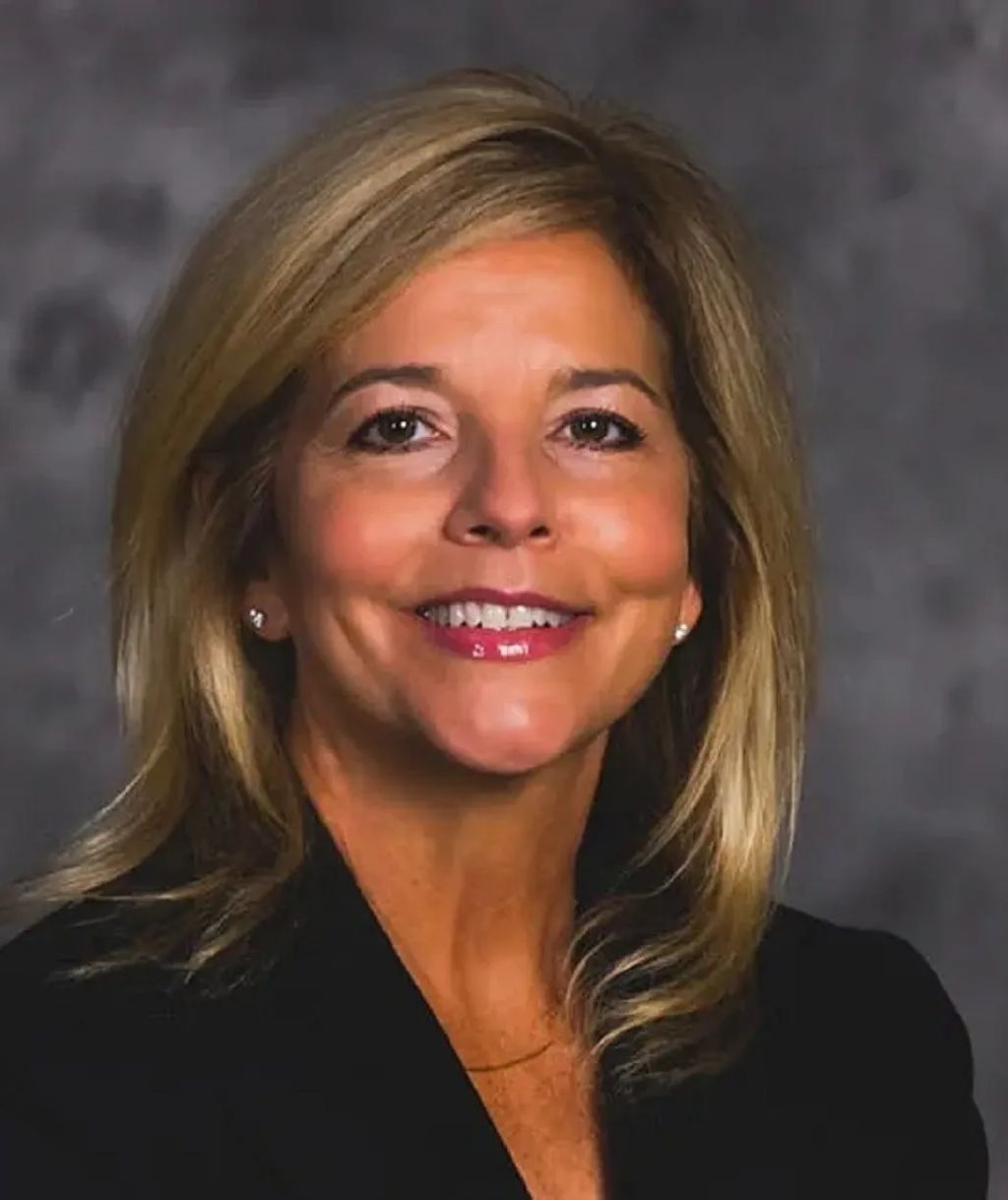 Smiling woman in a black top against a gray studio backdrop