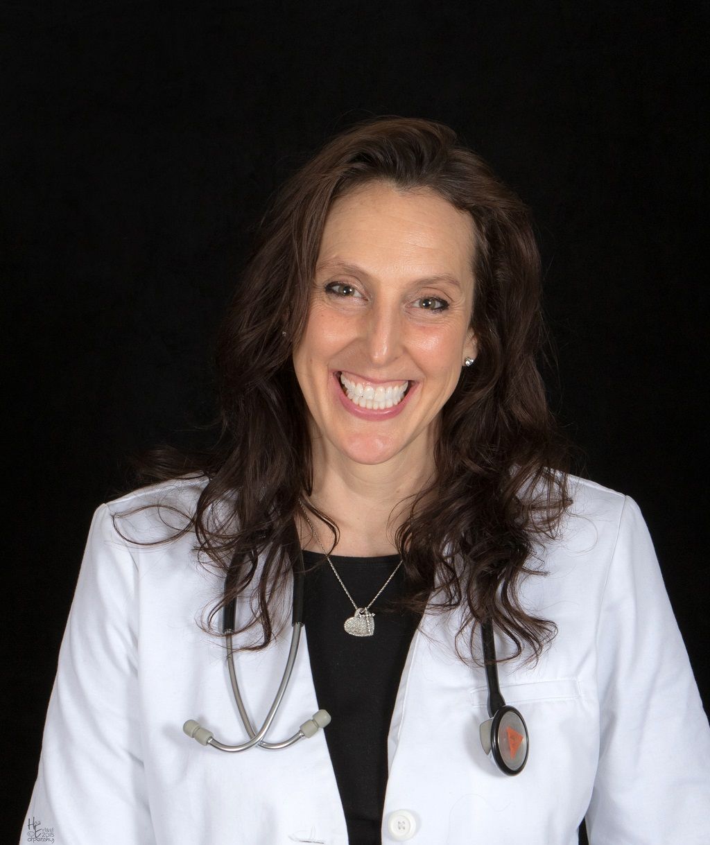 Smiling person in a white lab coat and stethoscope against a black background