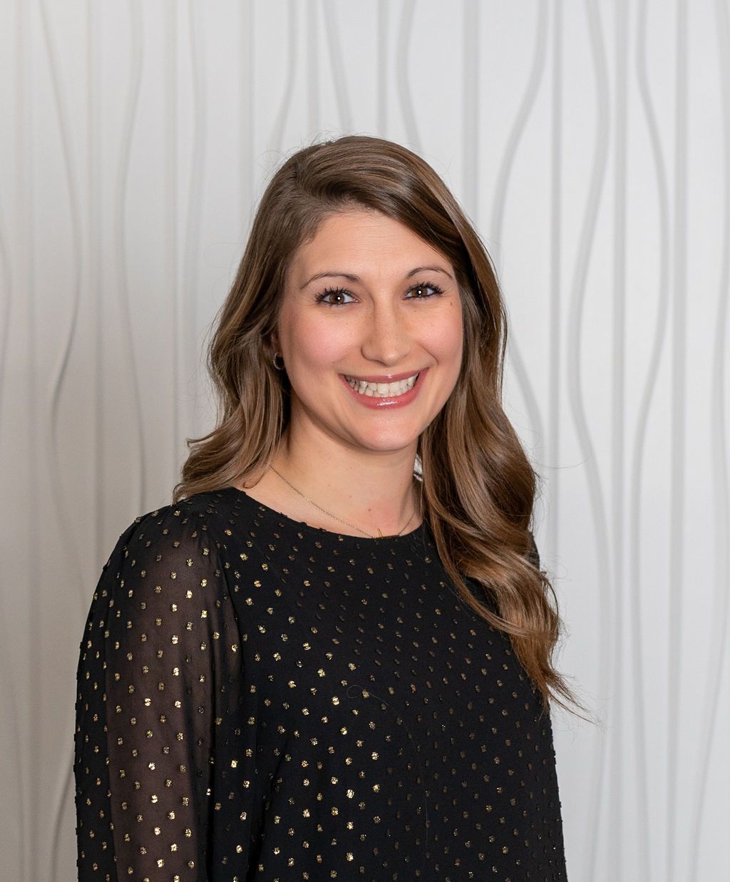 Smiling woman in a black blouse posing against a light gray backdrop