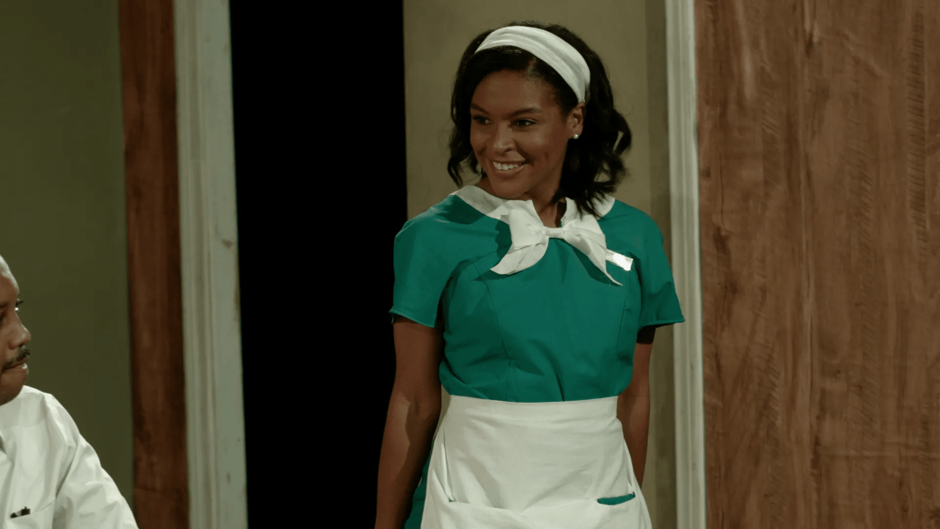 A woman in a maid 's uniform is standing in a doorway next to a man .
