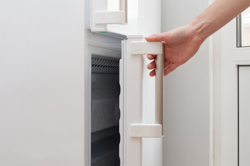 A Person's Hand Opening a White Refrigerator Door — SealTite in Terranora, NSW