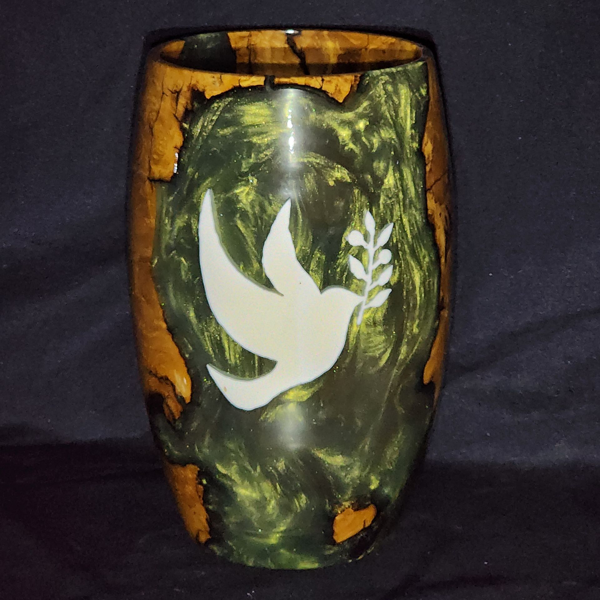 Wooden vase with orange and black patterns against a dark gray background.