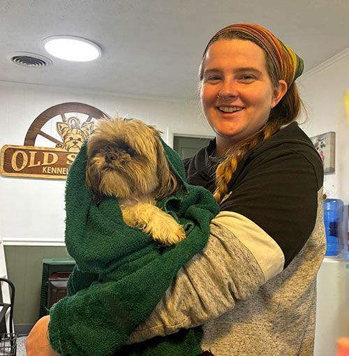 Woman holding a small dog wrapped in a green blanket inside a restaurant or café