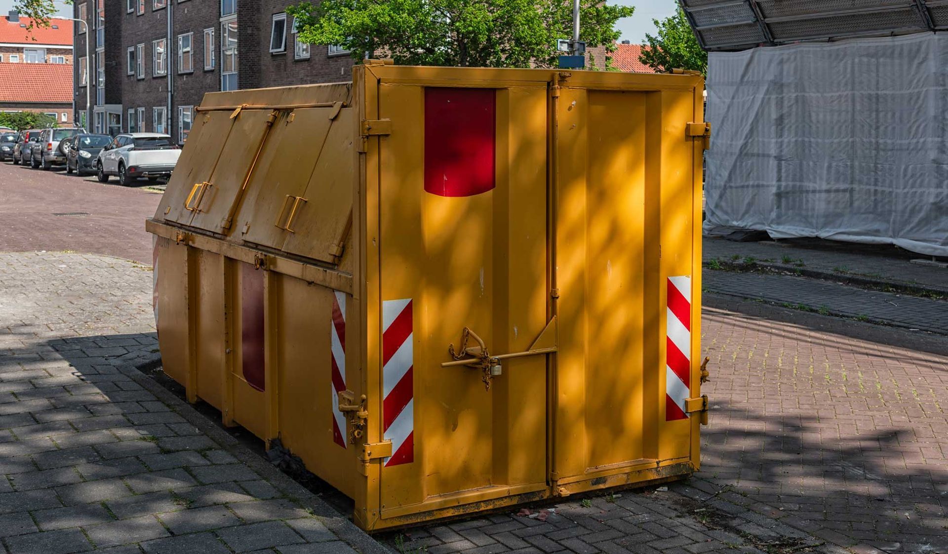 Large, yellow-lidded bin used for a residential dumpster rental on a city street.