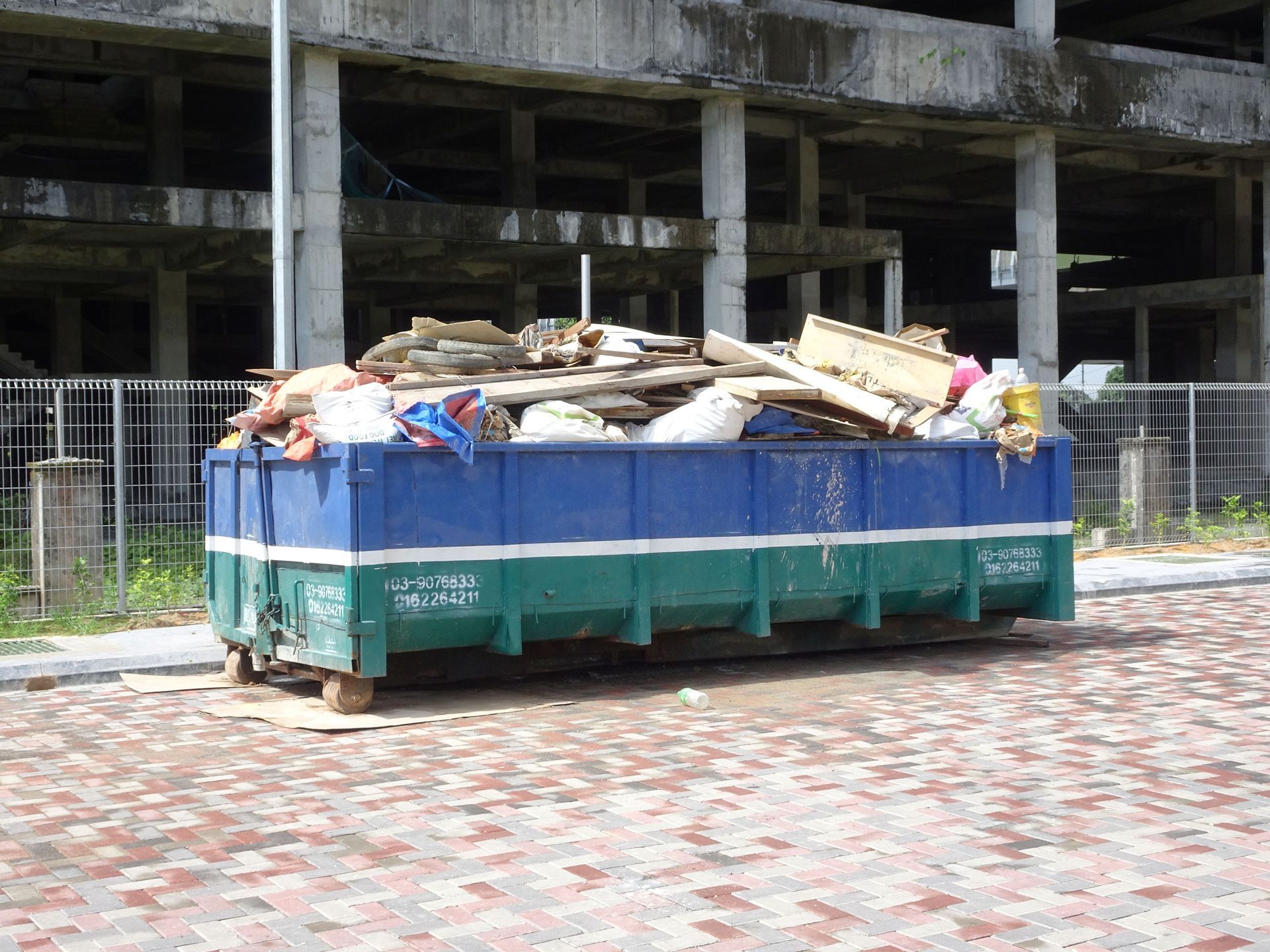 Roll-off dumpster rental bin collecting construction waste & unused materials at an active job site. Roll-off dumpster rental bin collecting construction waste & unused materials at an active job site.